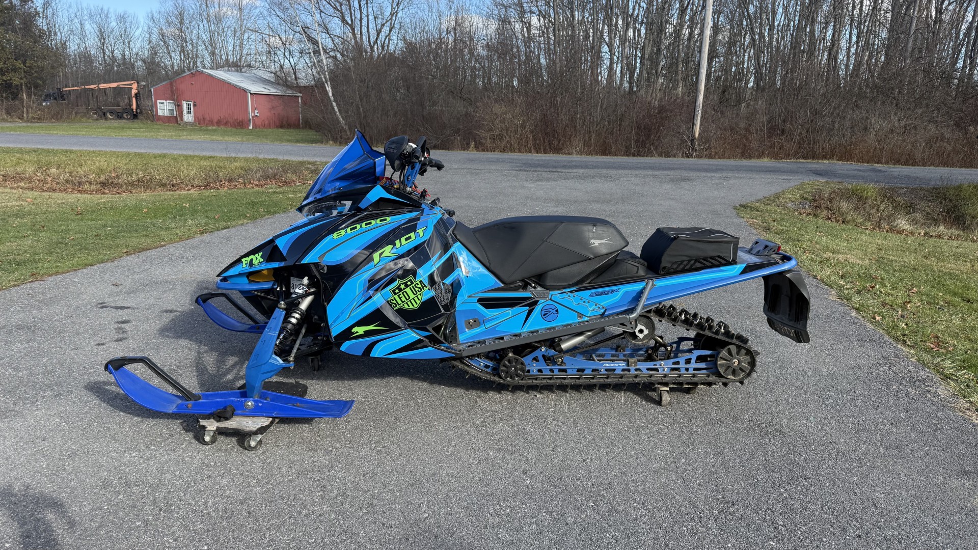 An ArcticCat Next-Gen snowmobile with a black, white, octane blue, and polar blue Sled USA Inertia custom vinyl wrap.