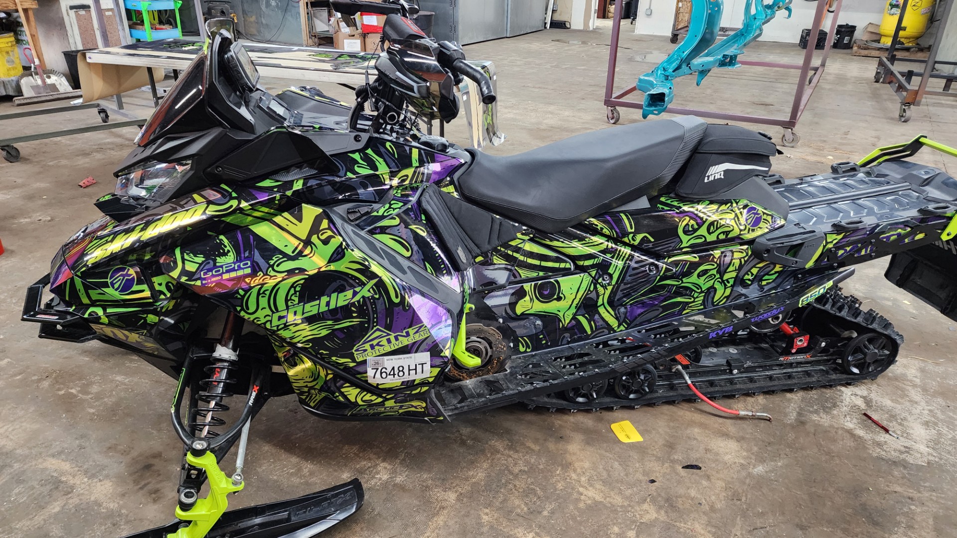 A Ski-Doo Gen4 Narrow Body snowmobile with a khaos purple, manta green, black, helio purple, and stealth gray Onasch Fueled custom vinyl wrap with chrome vinyl.