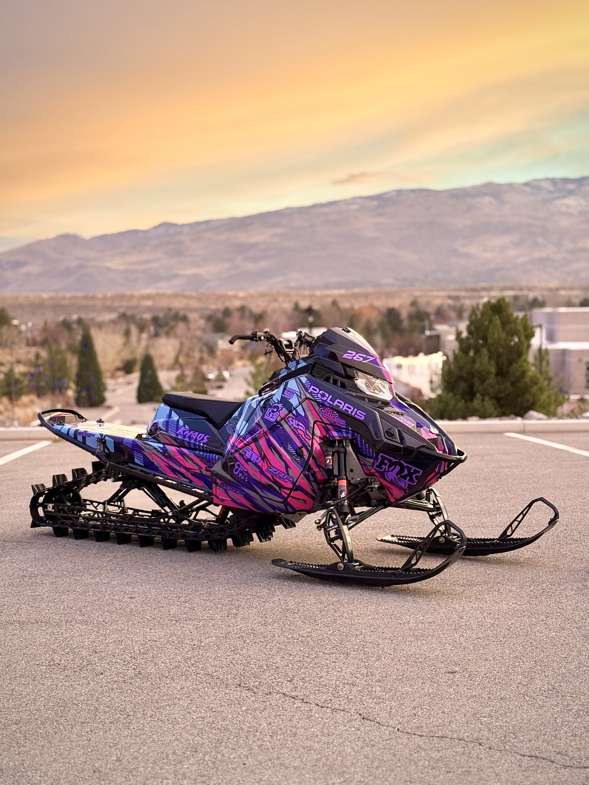 A Polaris Matryx Mountain snowmobile with a lilac purple, gunmetal gray, ink blue, stealth gray, hot pink, and violet purple Initialize custom vinyl wrap.