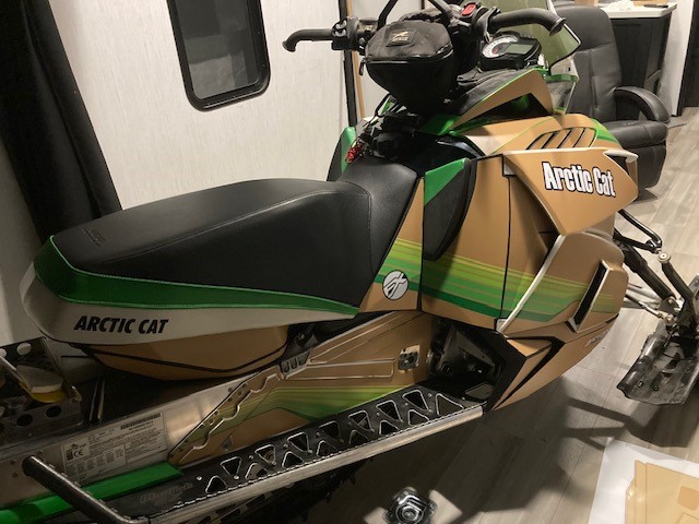 An ArcticCat Proclimb snowmobile with a black, white, light brown, pearl green, electric green, lime green, and hyper green Retro Cat custom vinyl wrap with matte laminate.