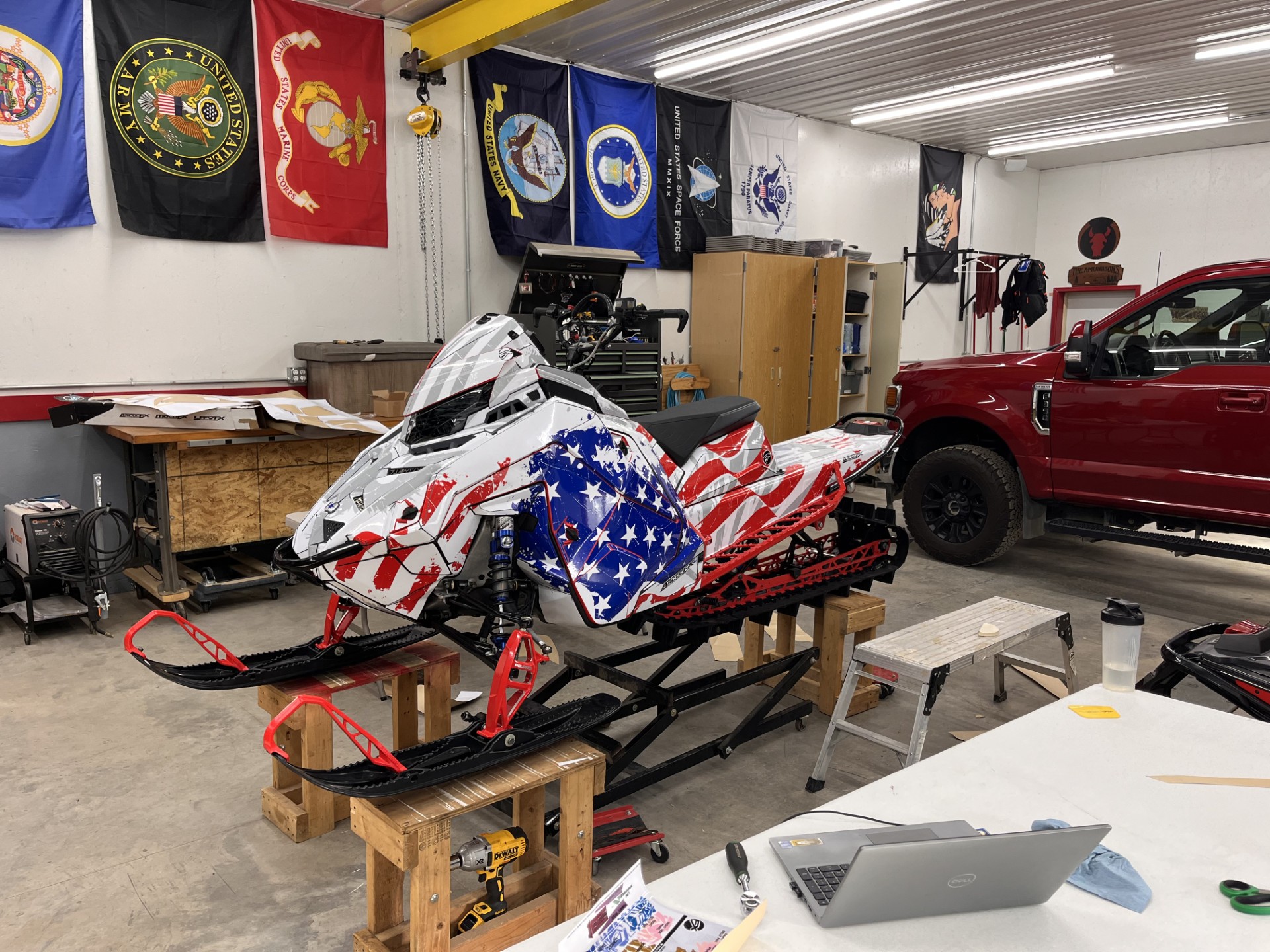 A Polaris Matryx Mountain snowmobile with a white, light gray, polar blue, and Polaris red American Flag custom vinyl wrap.