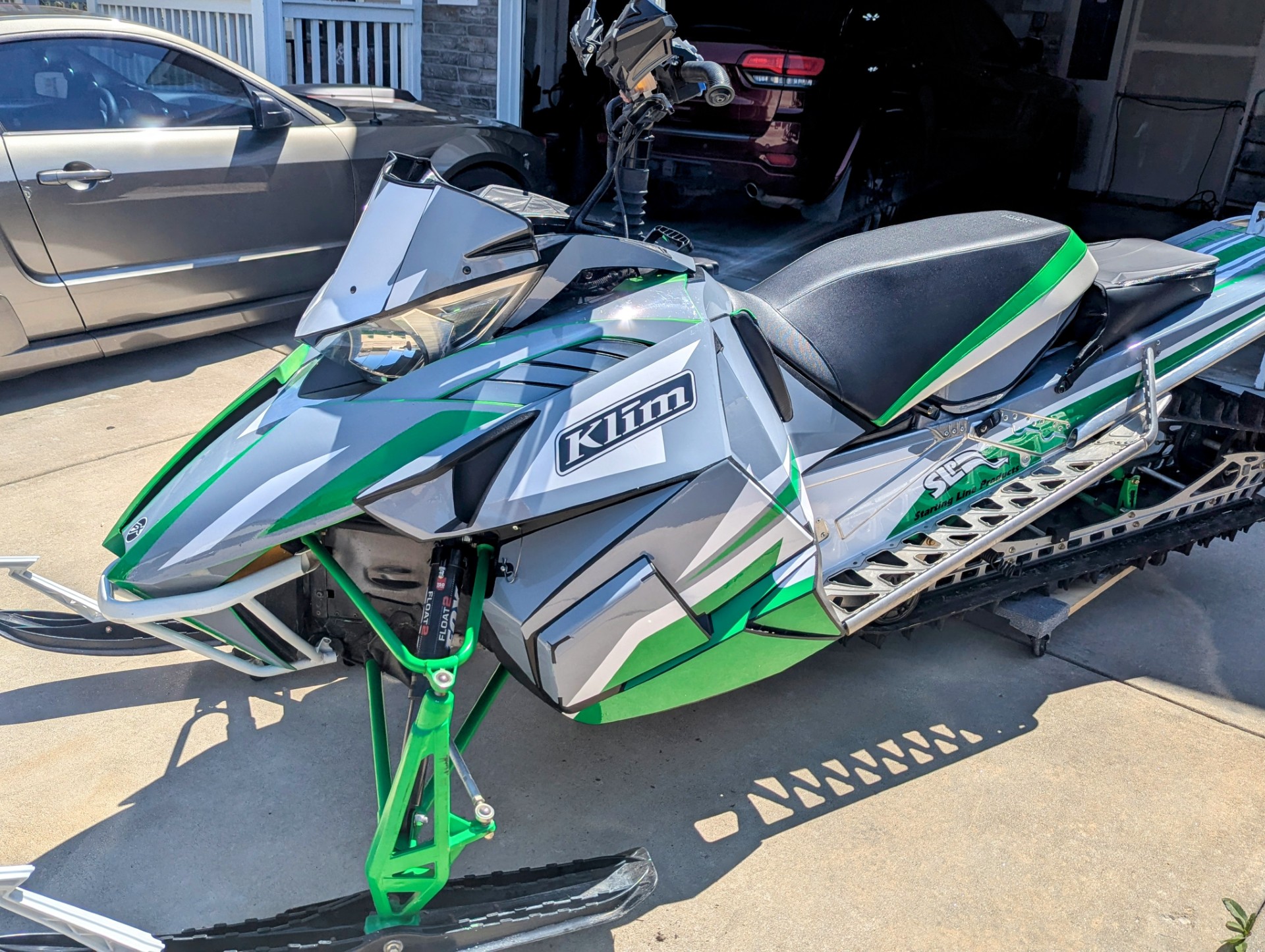 A ArcticCat Proclimb snowmobile with a white, black, monument gray, and pearl green Justin Thomas Velocity custom vinyl wrap.