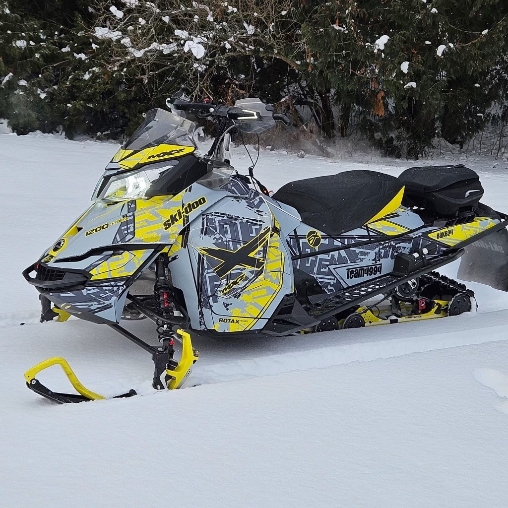 A SkiDoo Rev XS snowmobile with a light gray, stealth gray, sunburst yellow, and black Havoc custom vinyl wrap with matte laminate.