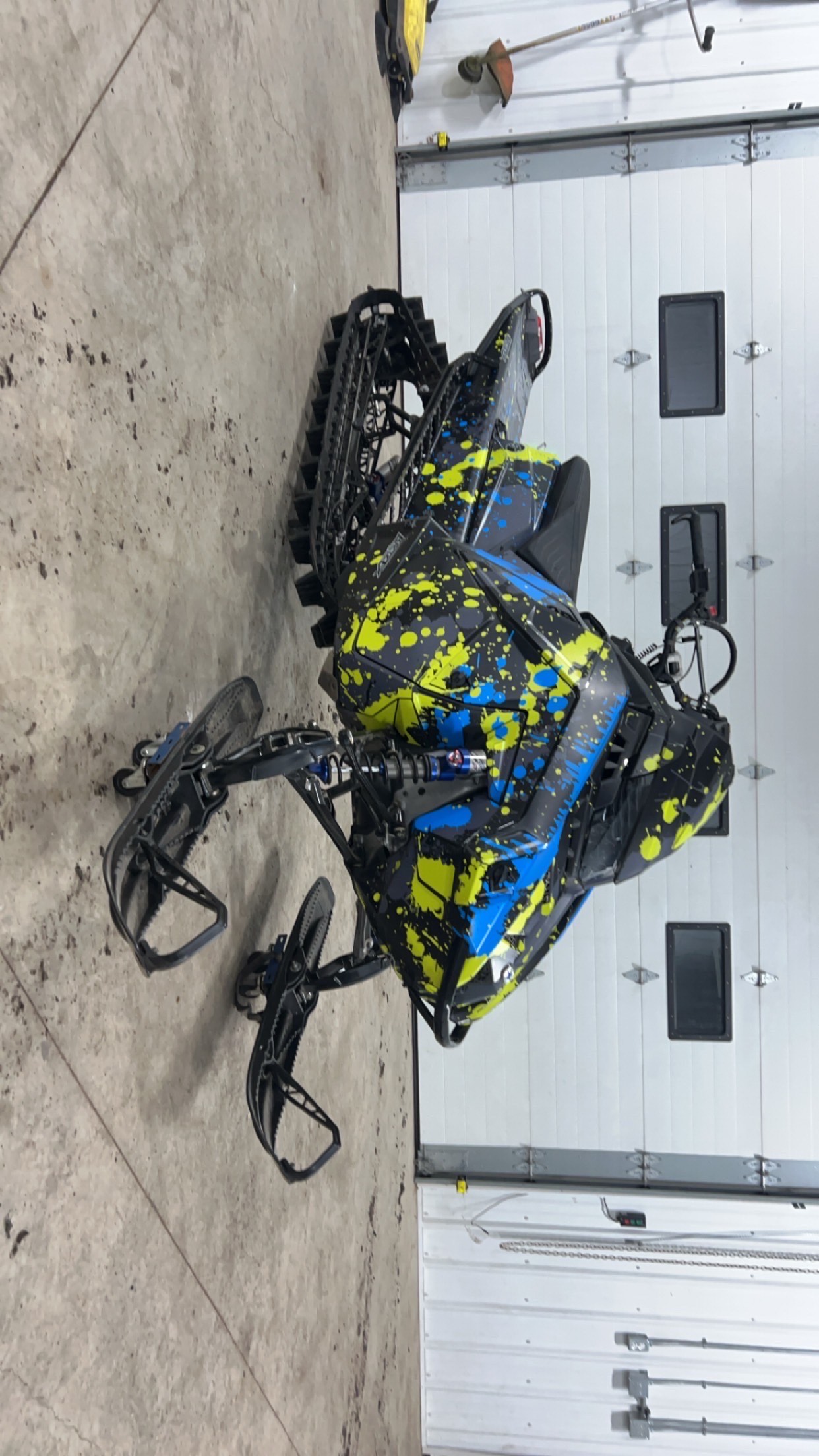 A Polaris Matryx Mountain snowmobile with a black, stealth gray, lime squeeze, sky blue, and light gray Dribble custom vinyl wrap with matte laminate.