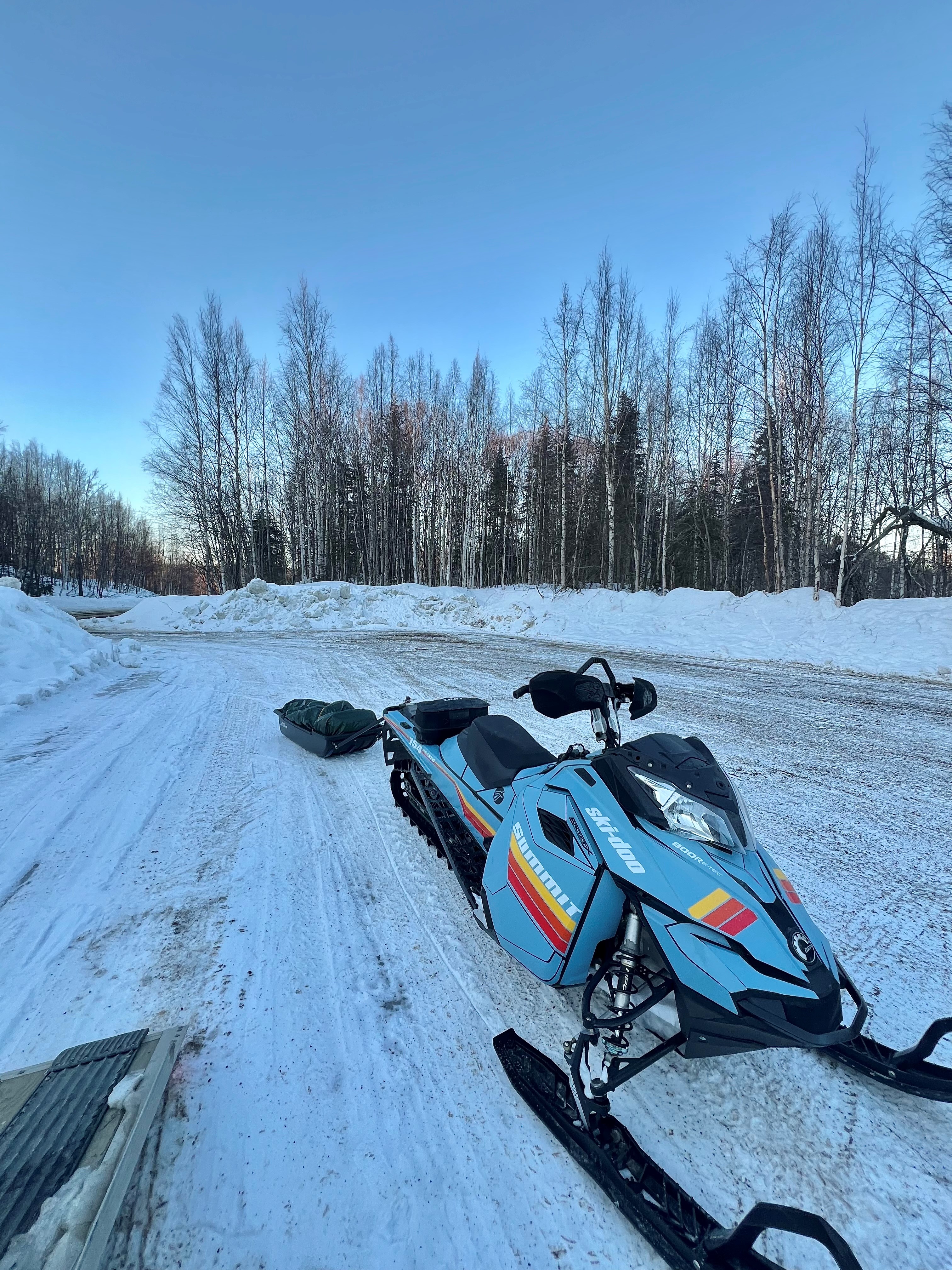 A SkiDoo Rev XM snowmobile with a custom colorway scandinavian blue, XP yellow, orange, lava red, white, and black Retro MX custom vinyl wrap with matte laminate.