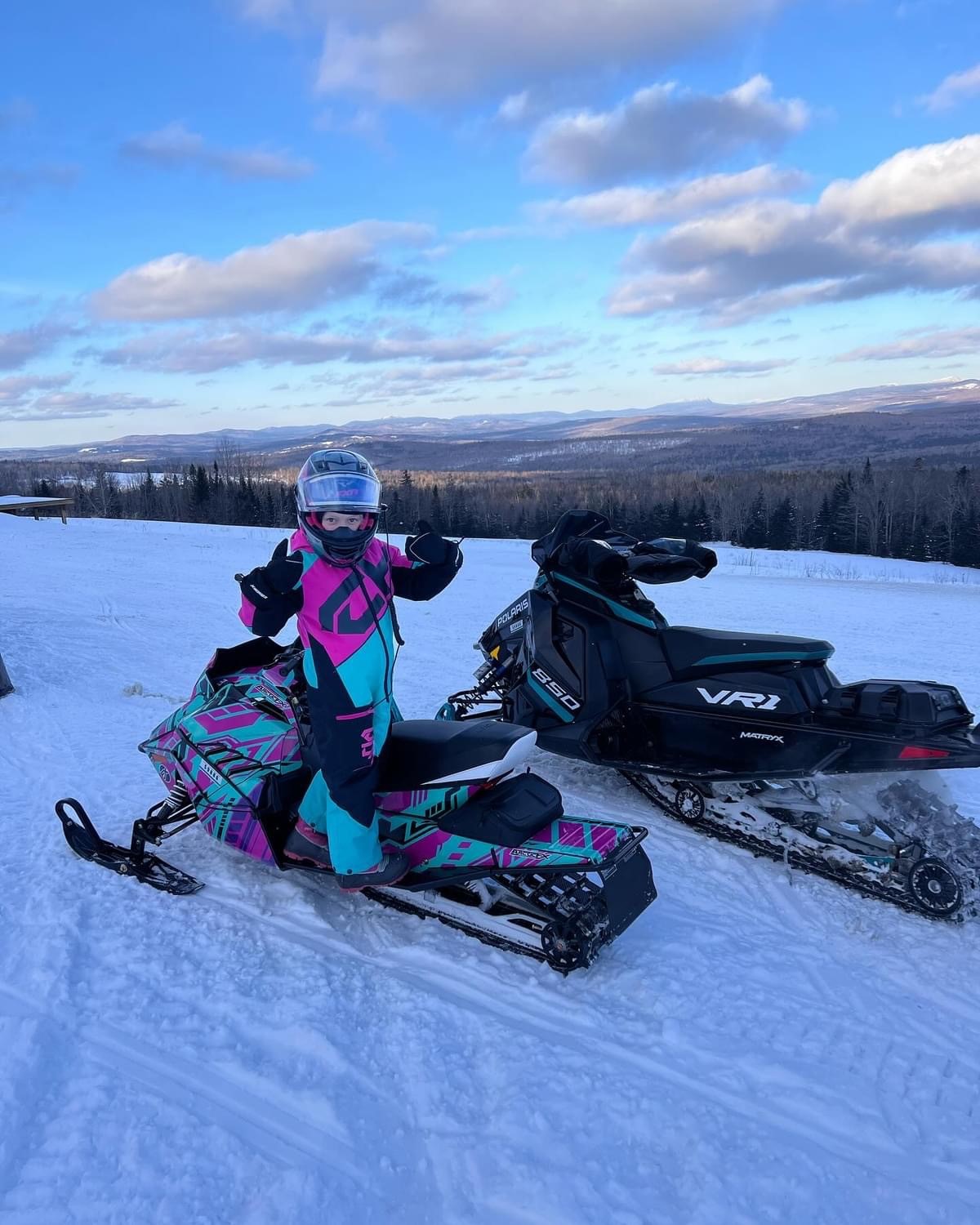 An ArcticCat ZR 200 snowmobile with a white, black, aqua blue, hot pink, and alpha purple Evasion custom vinyl wrap.