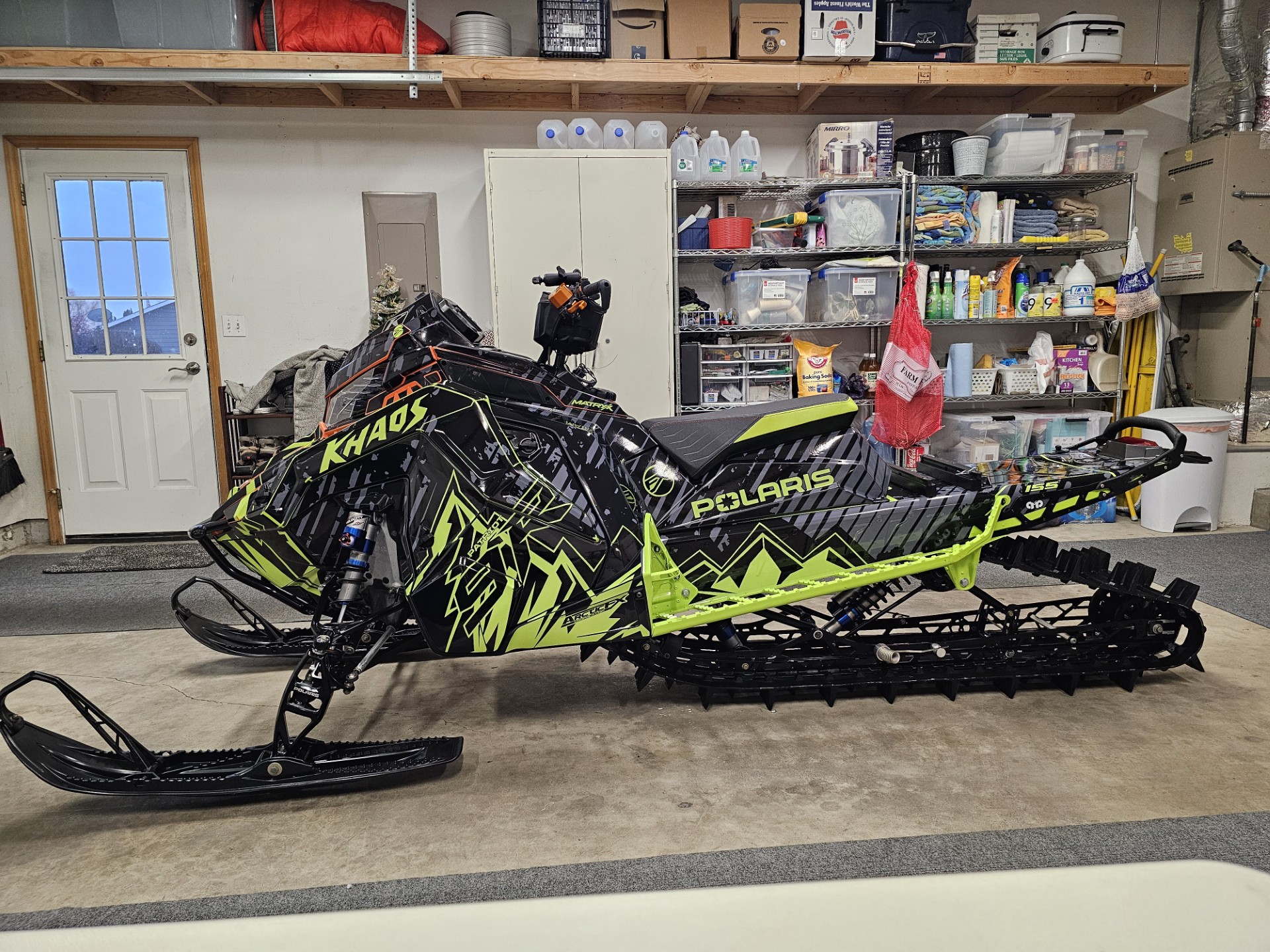 A Polaris Matryx Mountain snowmobile with a black, asphalt gray, and manta green Altitude custom vinyl wrap.