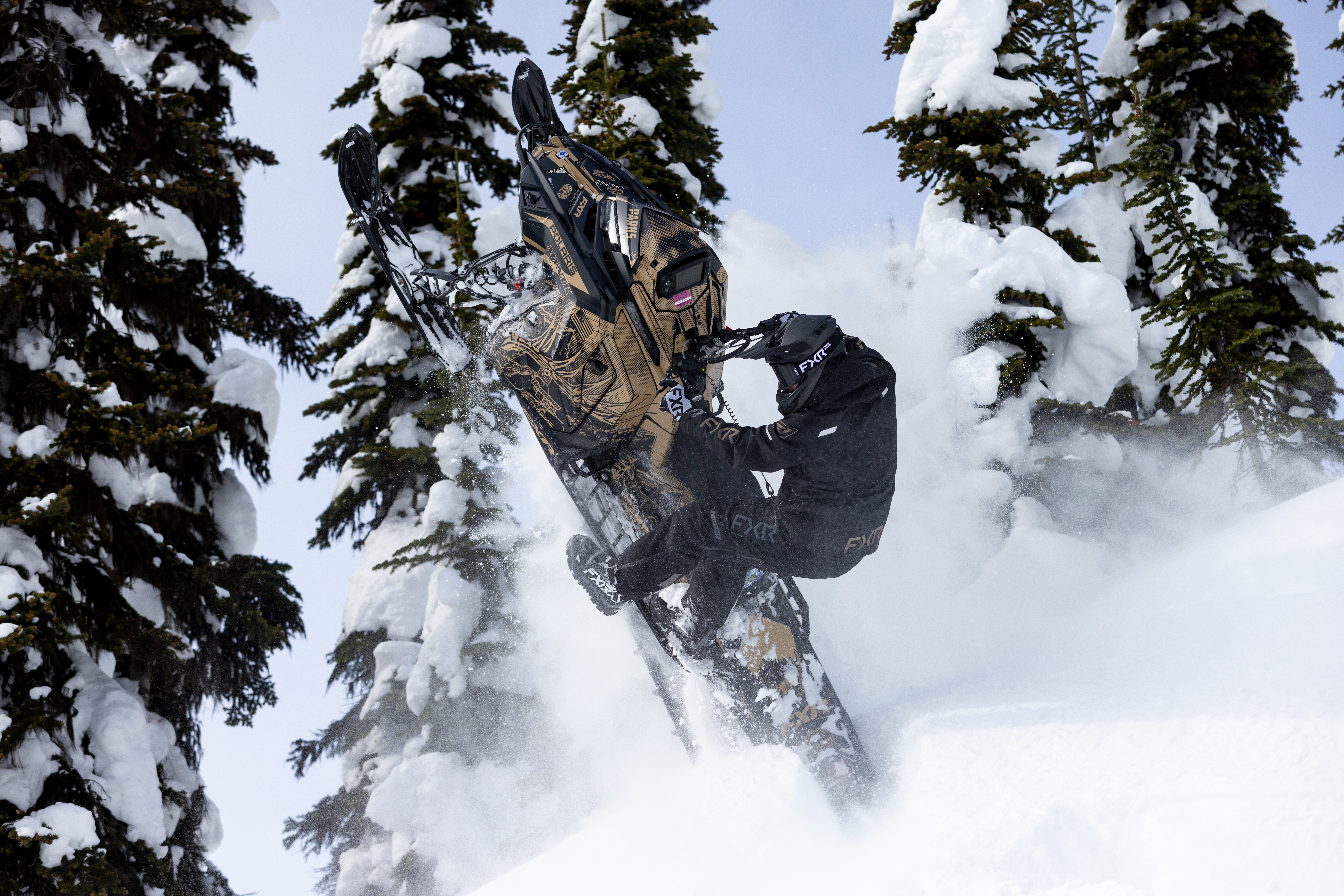A Polaris Matryx Mountain snowmobile with a military tan, black, and gunmetal gray Andy Thomas Attack custom vinyl wrap with matte laminate.