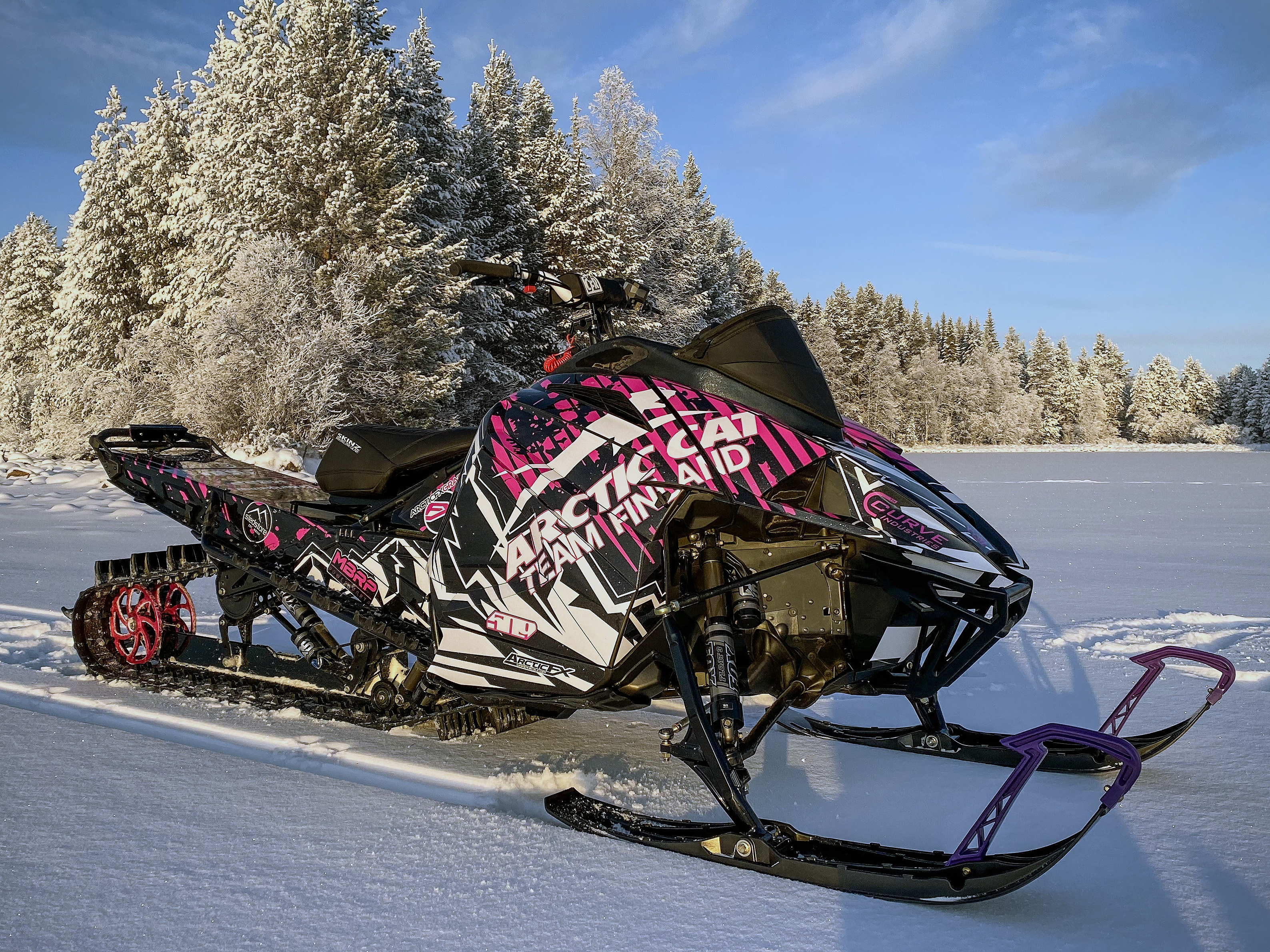 A Arctic Cat Ascender snowmobile with a pink, white, and black mountain Altitude custom vinyl wrap.