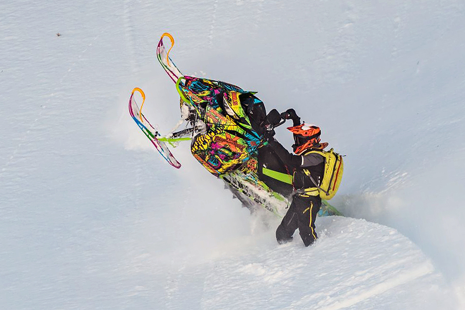 A Arctic Cat Ascender snowmobile with a green, yellow, pink, and blue yeti Leif Alvarsson Tree Slayer custom vinyl wrap.