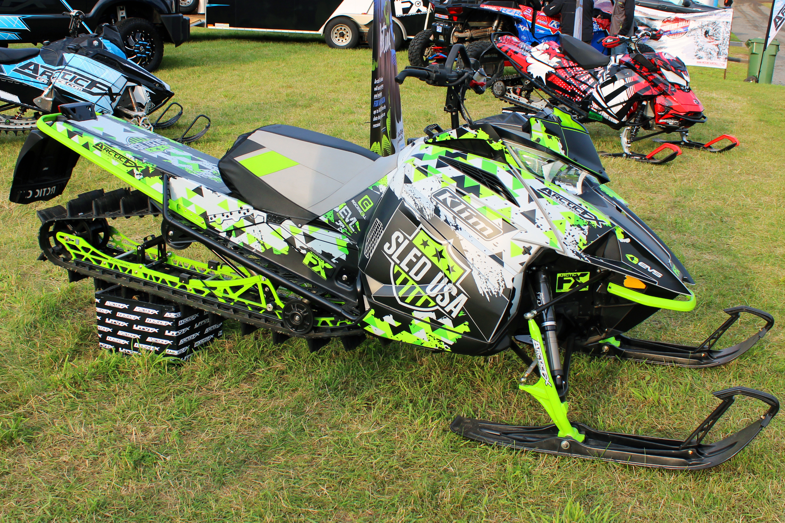 A Arctic Cat Ascender snowmobile with a green, gray, and black geometric pattern Aspect custom vinyl wrap.