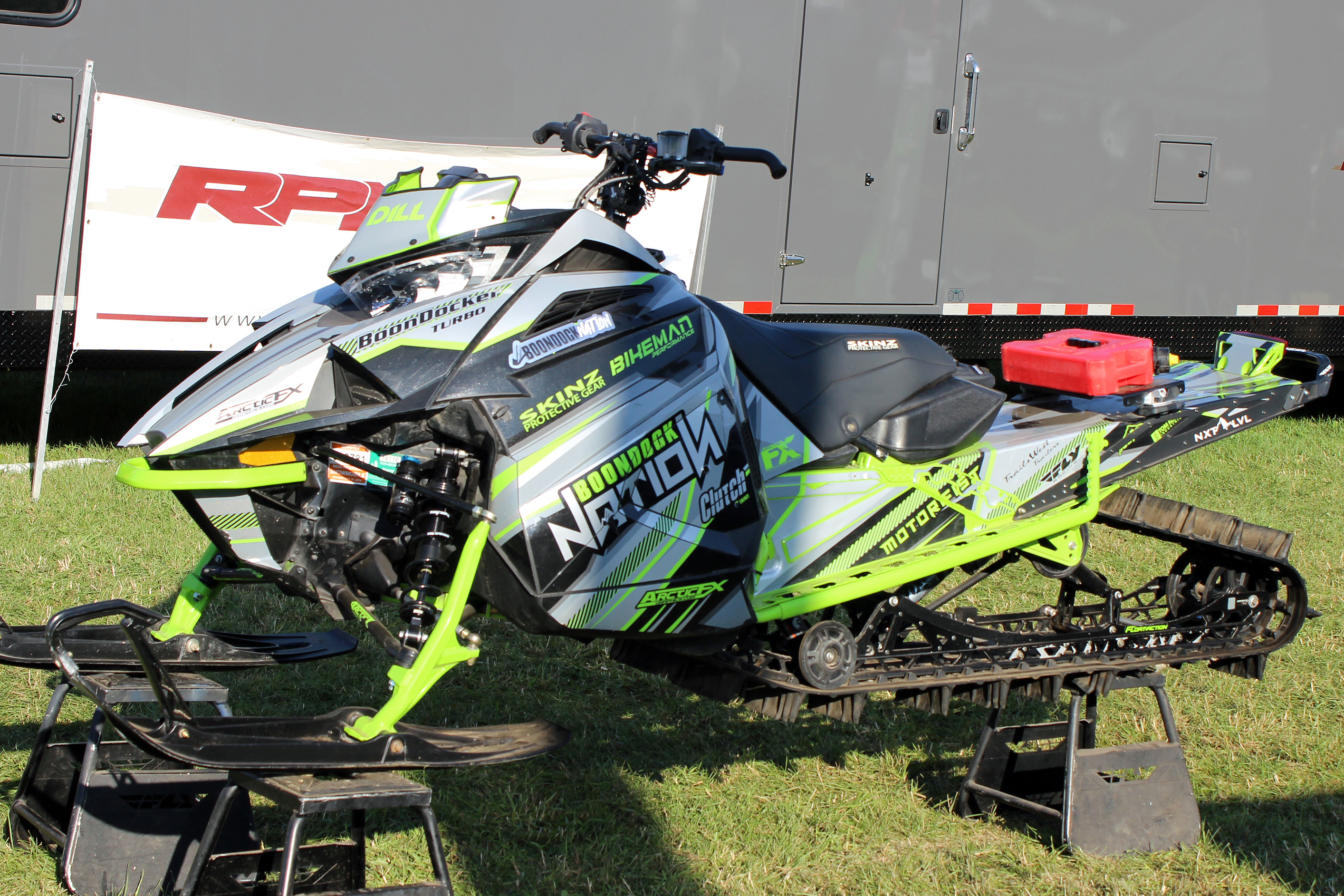 A Arctic Cat Ascender snowmobile with a green, gray, and black stripes Bred2Win custom vinyl wrap.