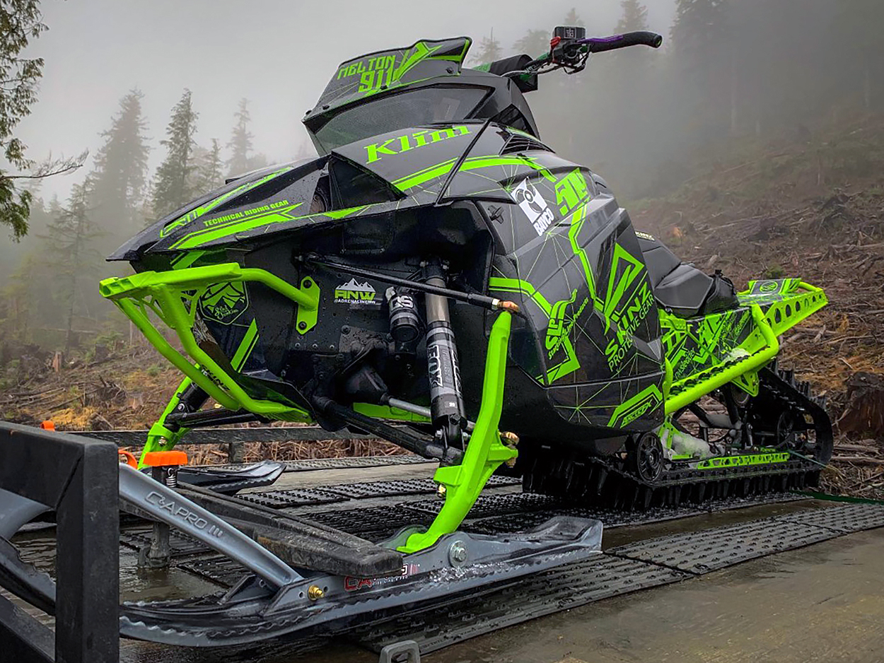 A Arctic Cat Ascender snowmobile with a green and gray geometric line Klim Demolish custom vinyl wrap.