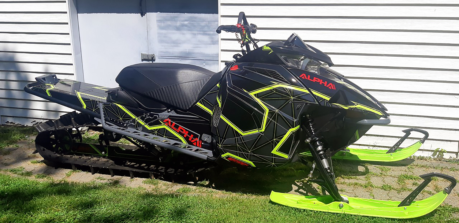 A Arctic Cat Ascender snowmobile with a lime squeeze, black and gray geometric line Klim Demolish custom vinyl wrap.
