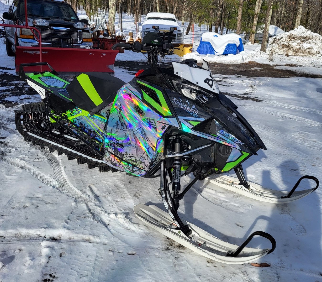 An Arctic Cat Ascender snowmobile with a green and black Andy thomas Peaked custom prismatic chrome vinyl wrap.