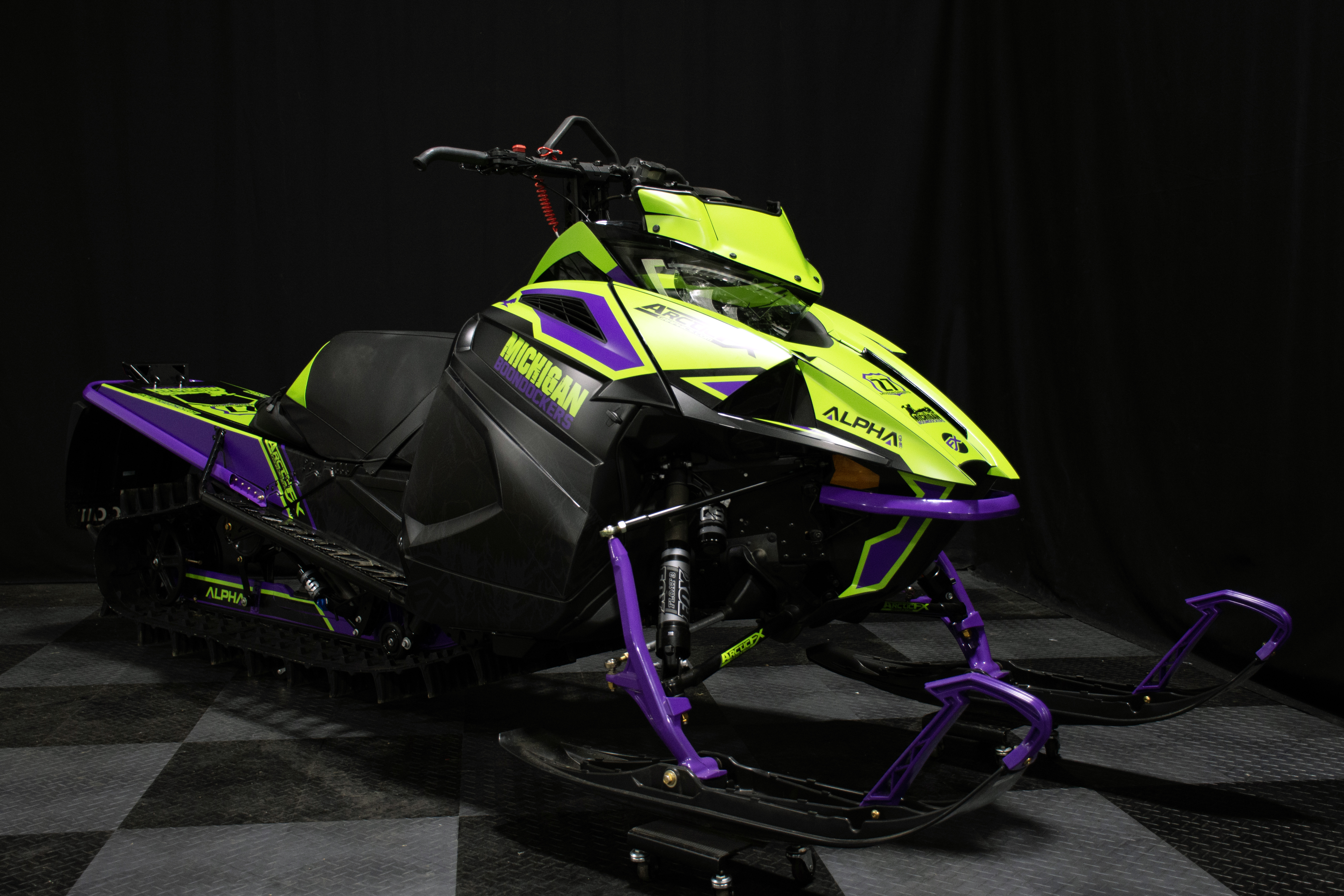 A Arctic Cat Ascender snowmobile with a green, gray, and black mountain Andy Thomas Peaked custom vinyl wrap.