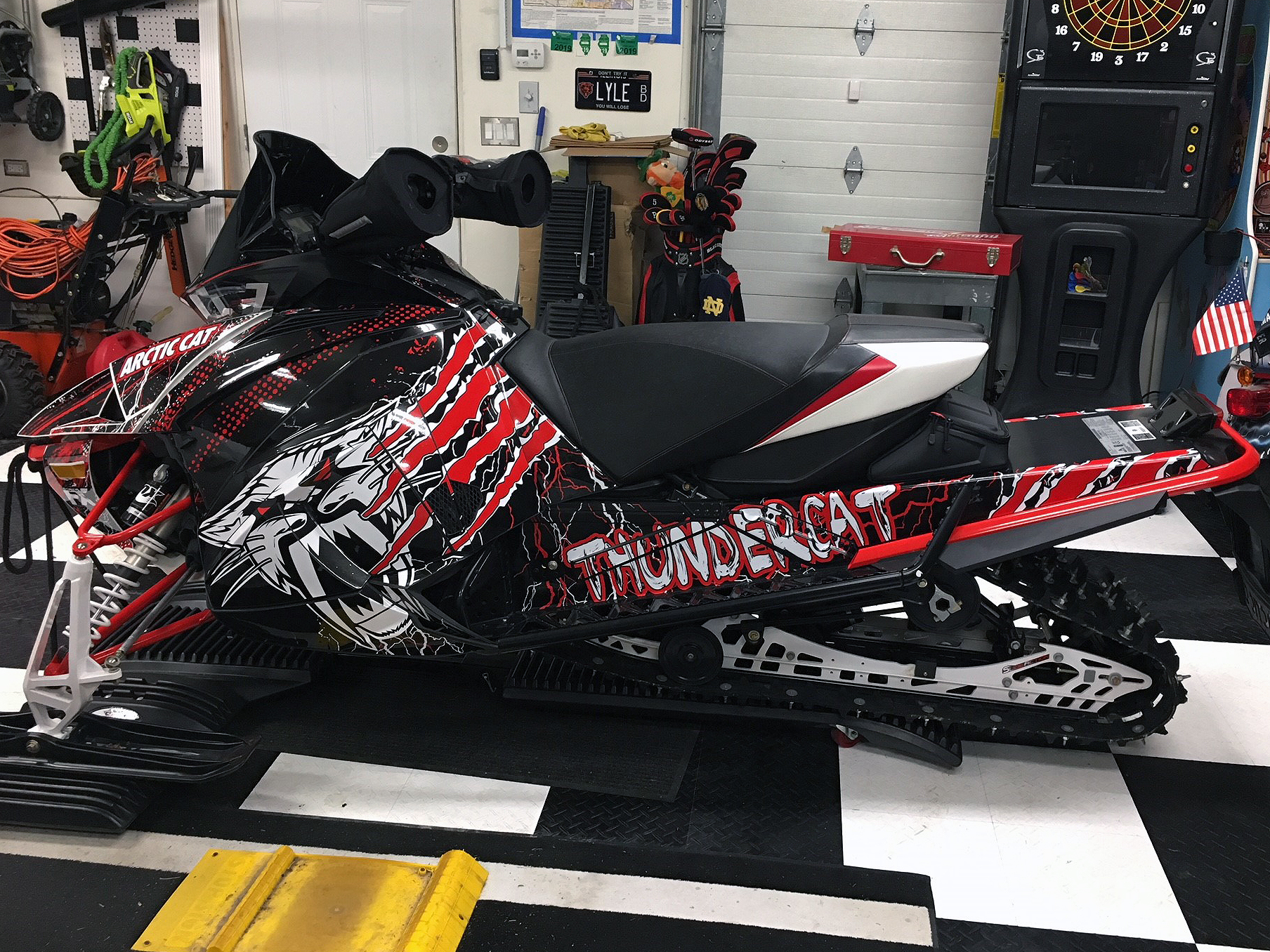 A Arctic Cat Next-Gen snowmobile with a red, white, and black Cat Head Lightning custom vinyl wrap.