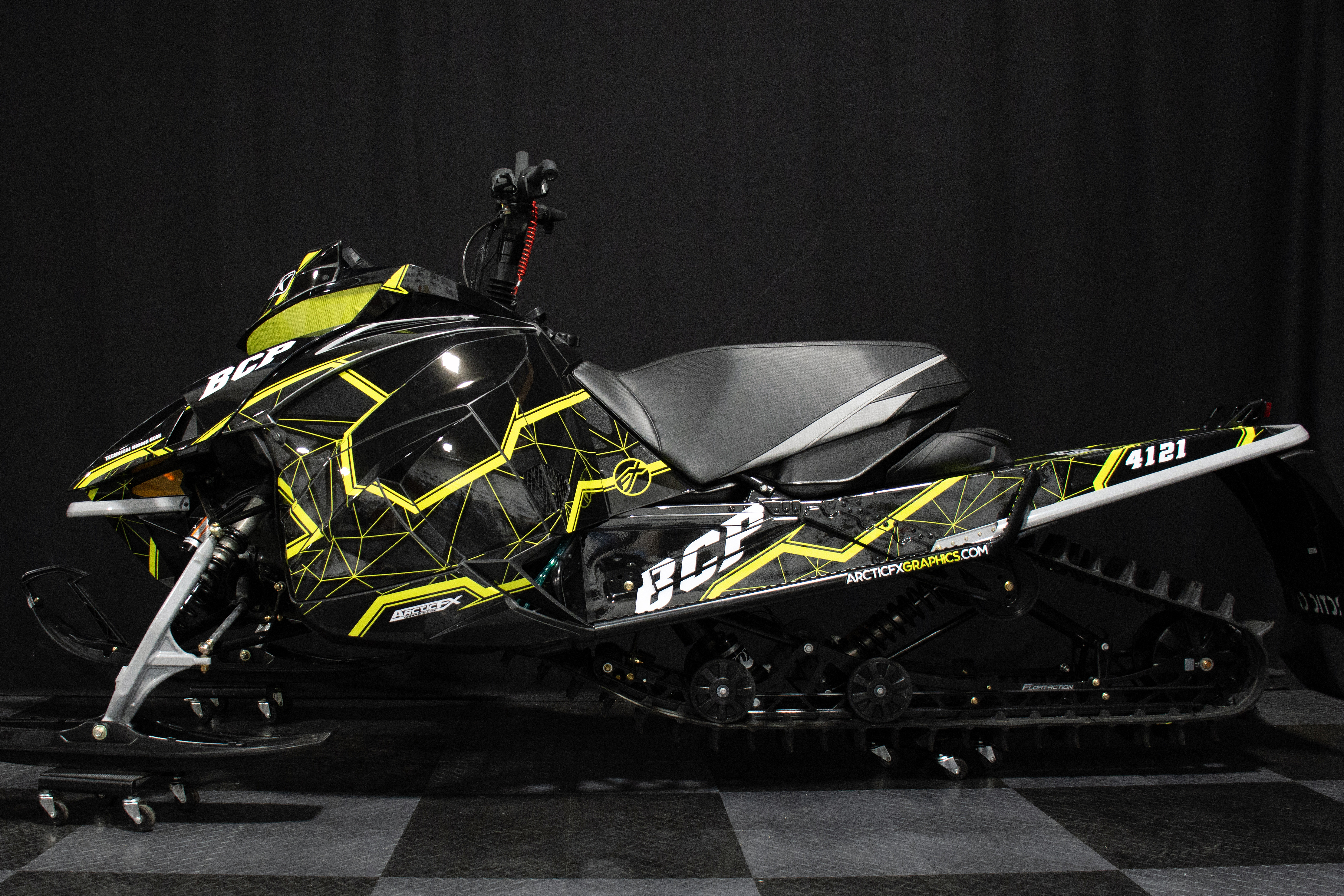 A Arctic Cat Next-Gen snowmobile with a black, gray, and lime squeeze Klim Demolish custom vinyl wrap.
