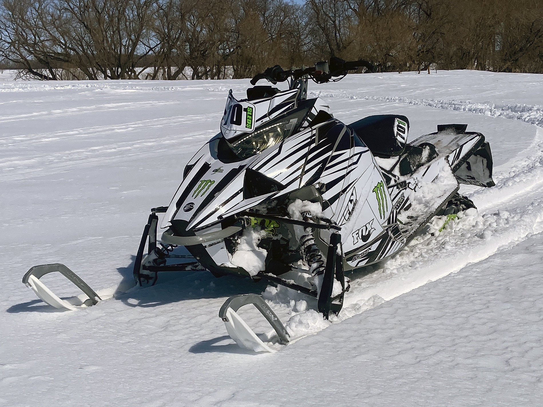 A Arctic Cat Next-Gen snowmobile with a black, green, and white Kryptonite custom vinyl wrap.
