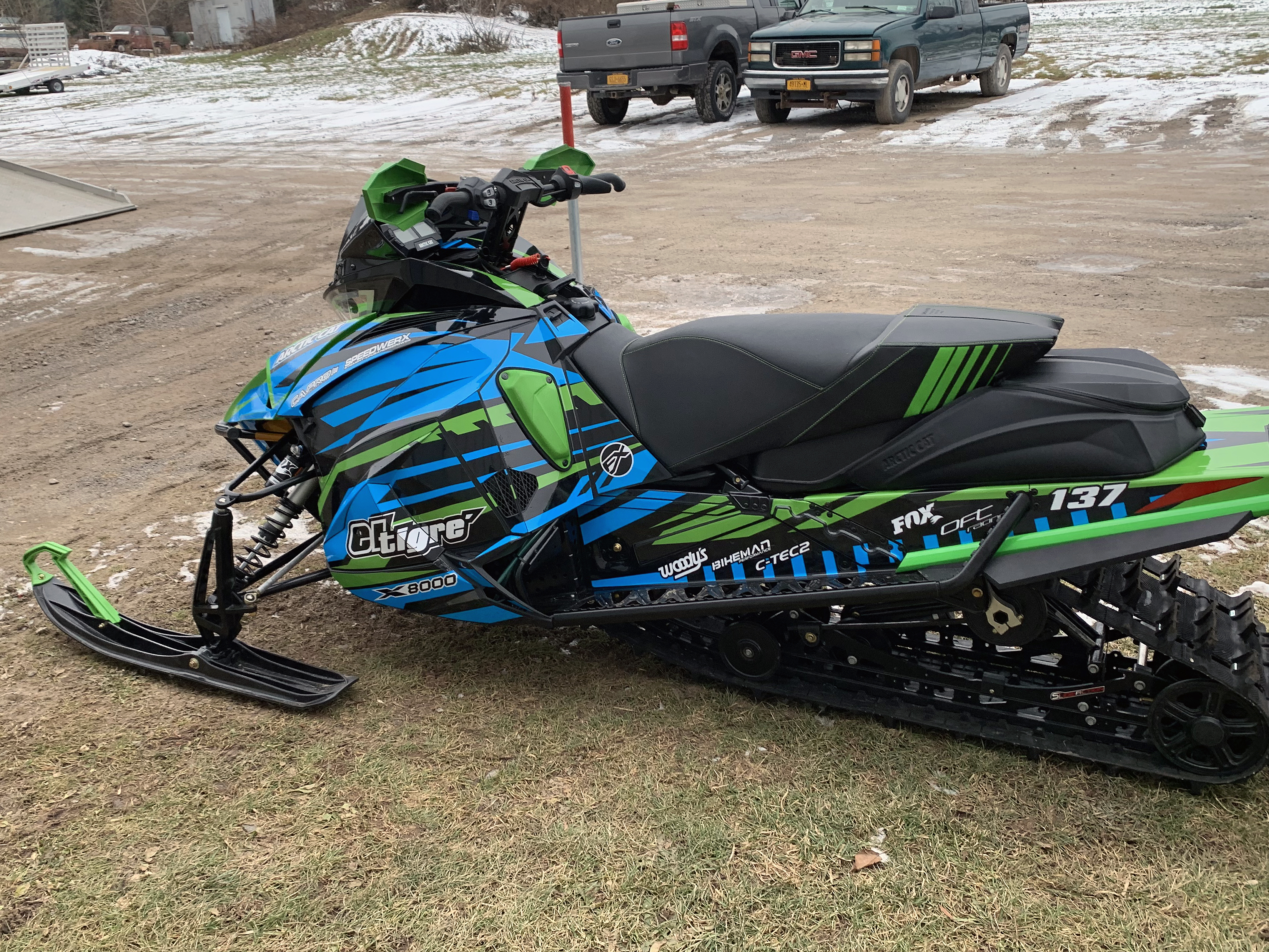 A Arctic Cat Next-Gen snowmobile with a blue, black, and green Relay custom vinyl wrap.