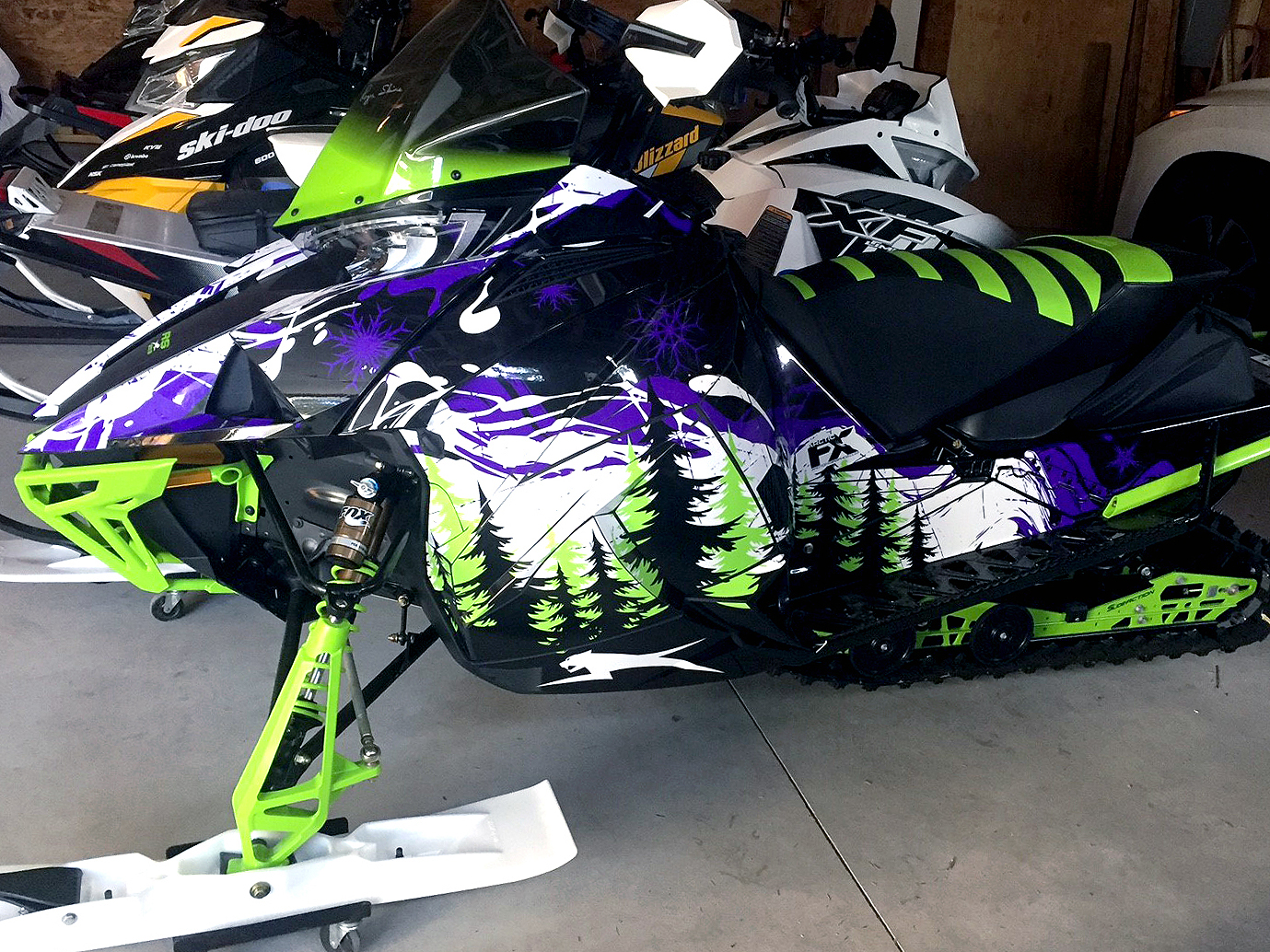 A Arctic Cat Next-Gen snowmobile with a black, green, purple, and white Sub Zero custom vinyl wrap.
