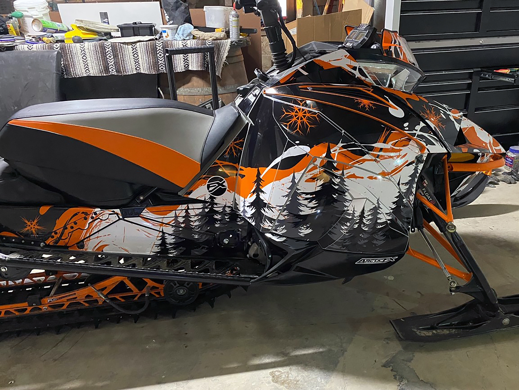 A Arctic Cat Next-Gen snowmobile with a black, orange, and white Sub Zero custom vinyl wrap.