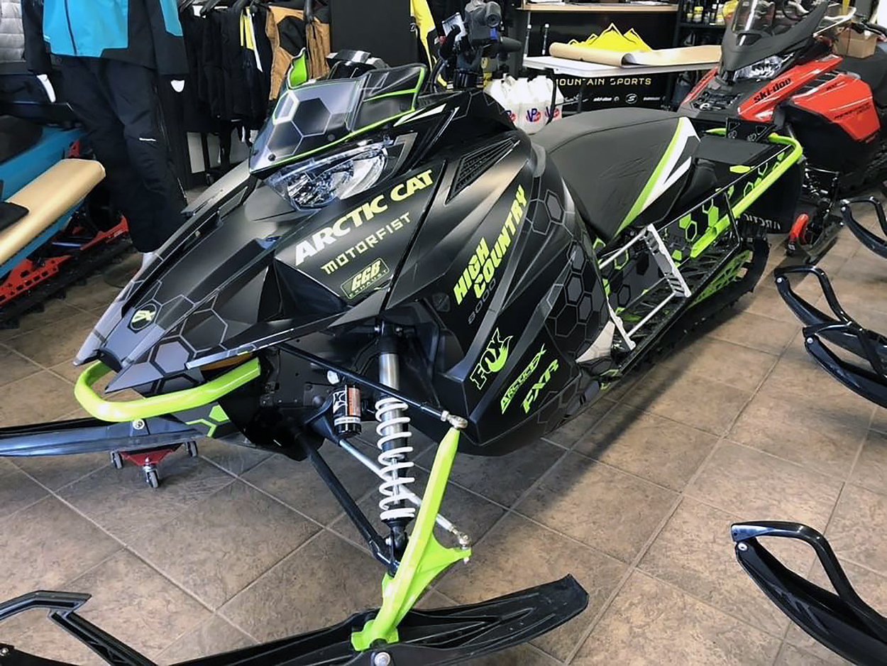 A Arctic Cat Next-Gen snowmobile with a black, lime, and gray Sync custom vinyl wrap.