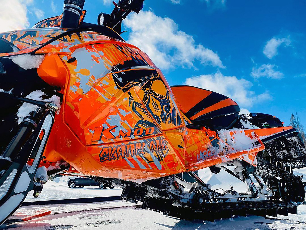 A Arctic Cat Next-Gen snowmobile with a orange, gray, and black Tagged custom vinyl wrap.