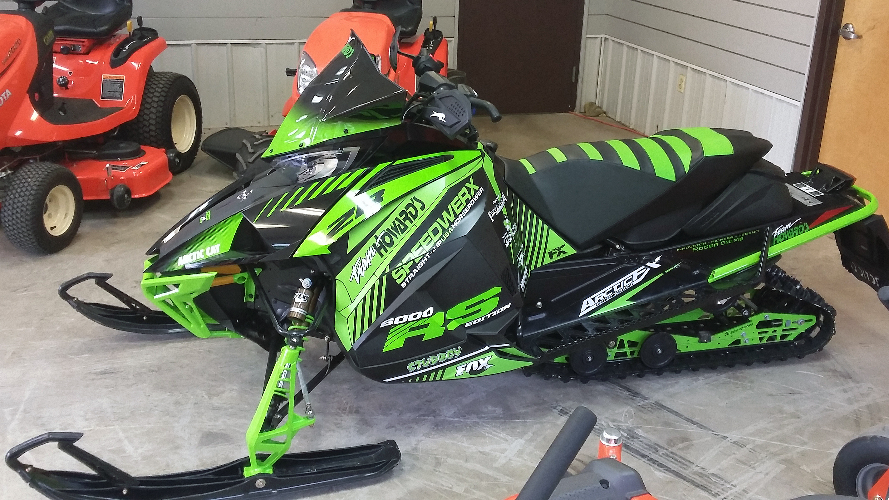 A Arctic Cat Next-Gen snowmobile with a green and black Team Howards custom vinyl wrap.