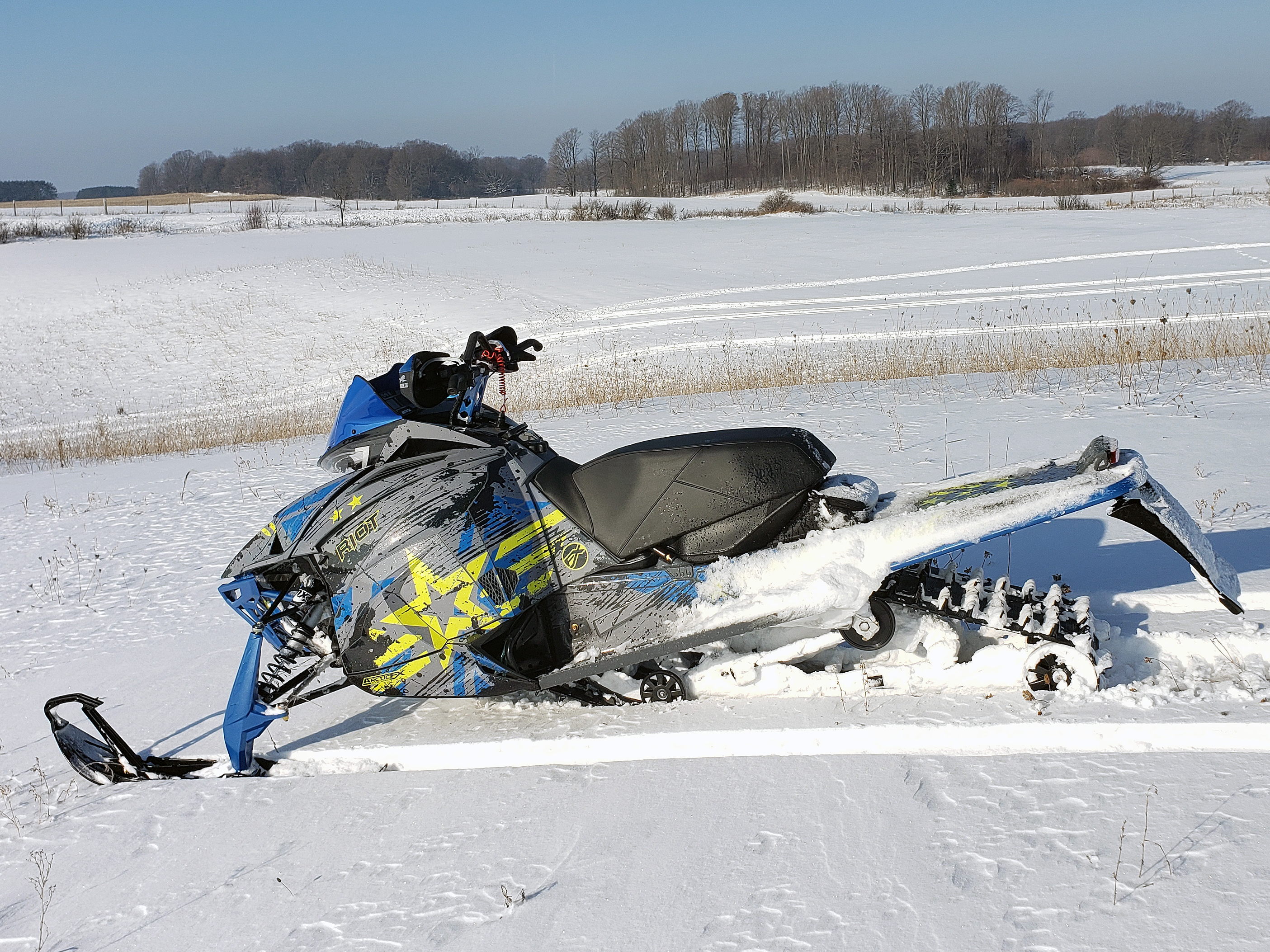 A Arctic Cat Next-Gen snowmobile with a gray, blue, and lime squeeze Wartorn custom vinyl wrap.