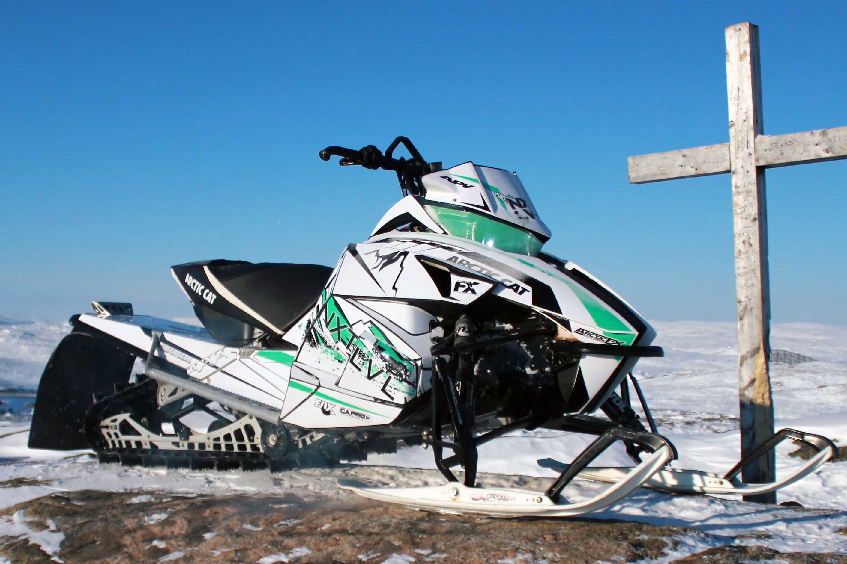 A Arctic Cat Proclimb snowmobile with a white, black, and aqua grunge mountain Adams Signature custom vinyl wrap.