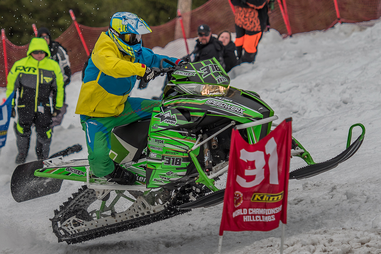 A Arctic Cat Proclimb snowmobile with a green, gold and black stripes Bred2Win custom vinyl wrap.