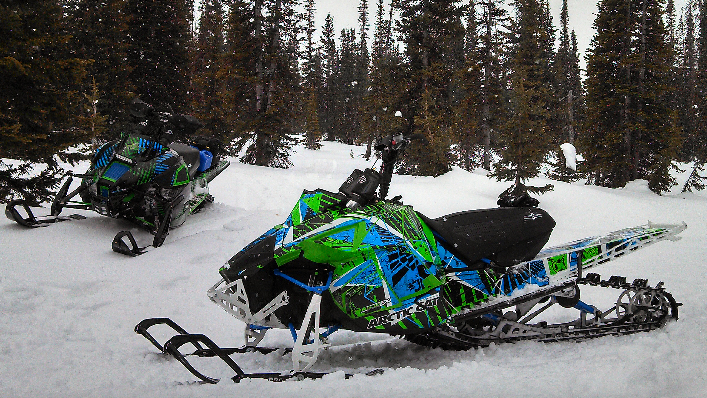 A Arctic Cat Proclimb snowmobile with a green, blue and white grunge Broken Arrow custom vinyl wrap.