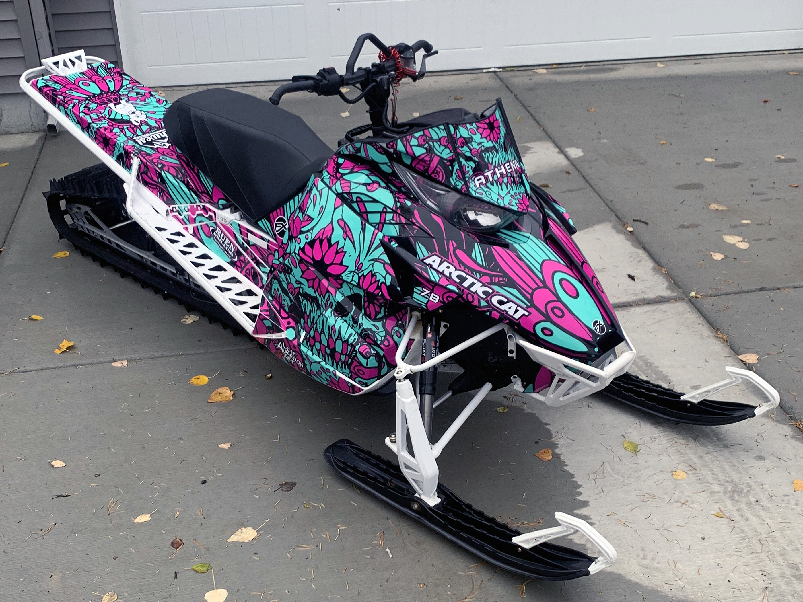 A Arctic Cat Procross snowmobile with a aqua, pink and black sugar skull Leif Alvarsson Calavera custom vinyl wrap.