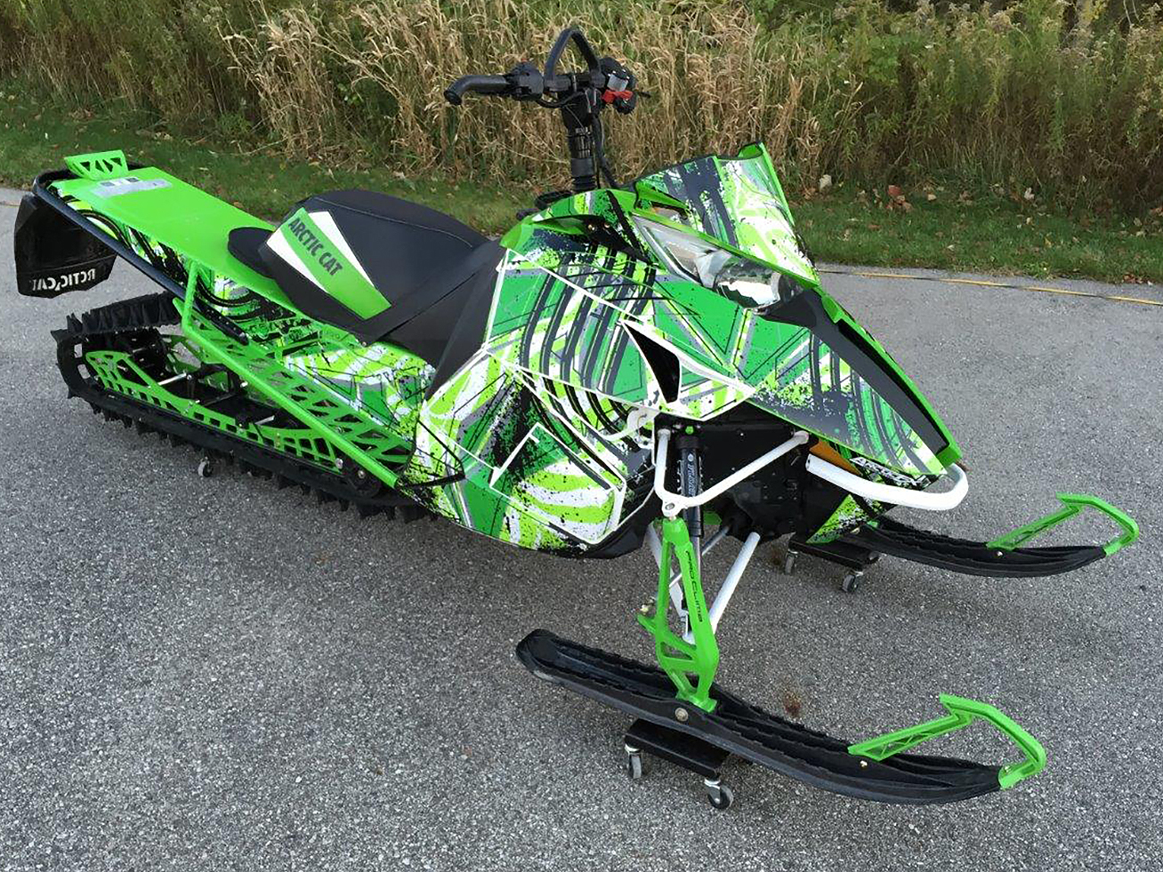 A Arctic Cat Proclimb snowmobile with a green, white and black grunge stripes Carnivore custom vinyl wrap.