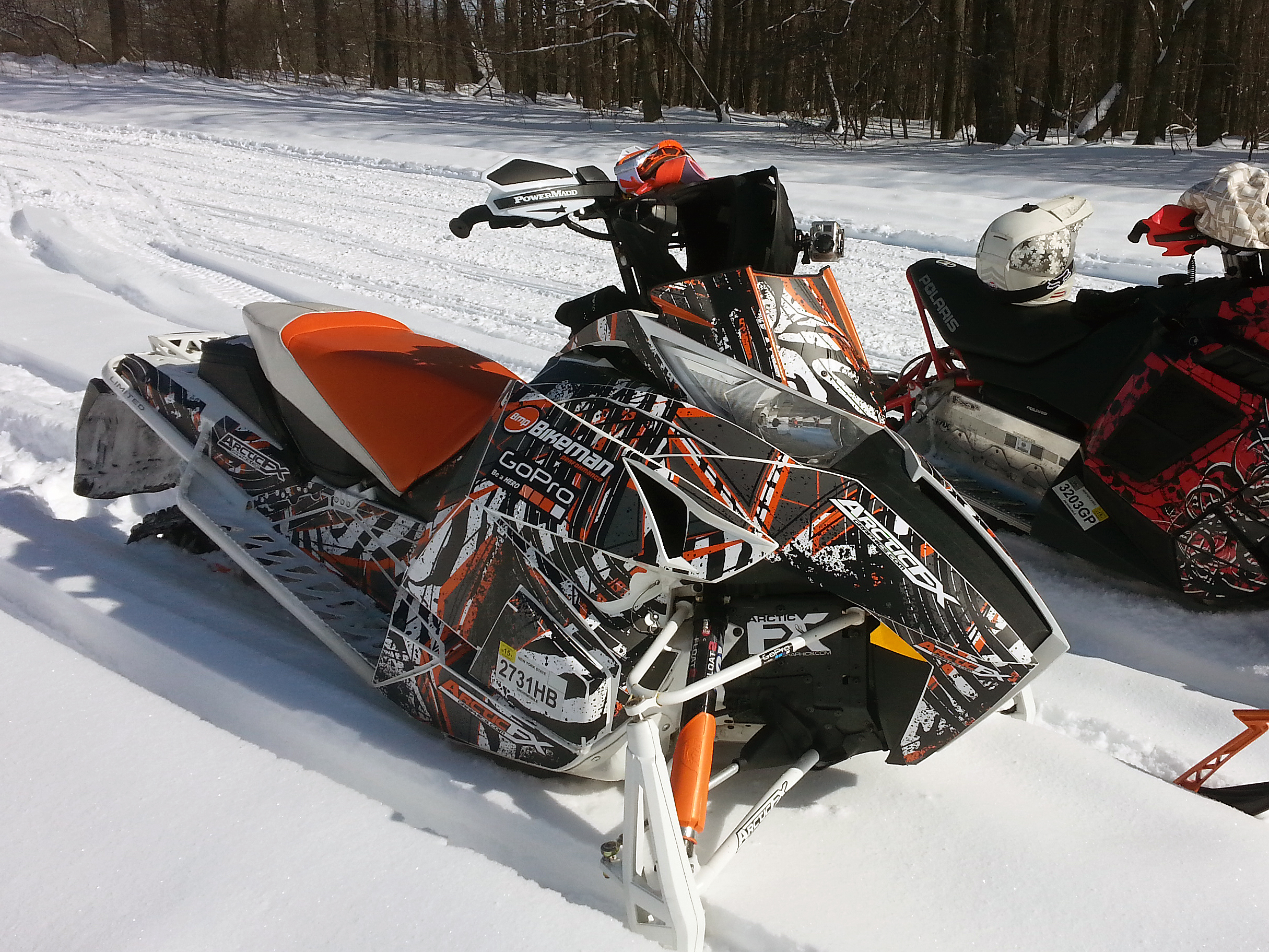 A Arctic Cat Procross snowmobile with a orange, white and black grunge stripes Carnivore custom vinyl wrap.