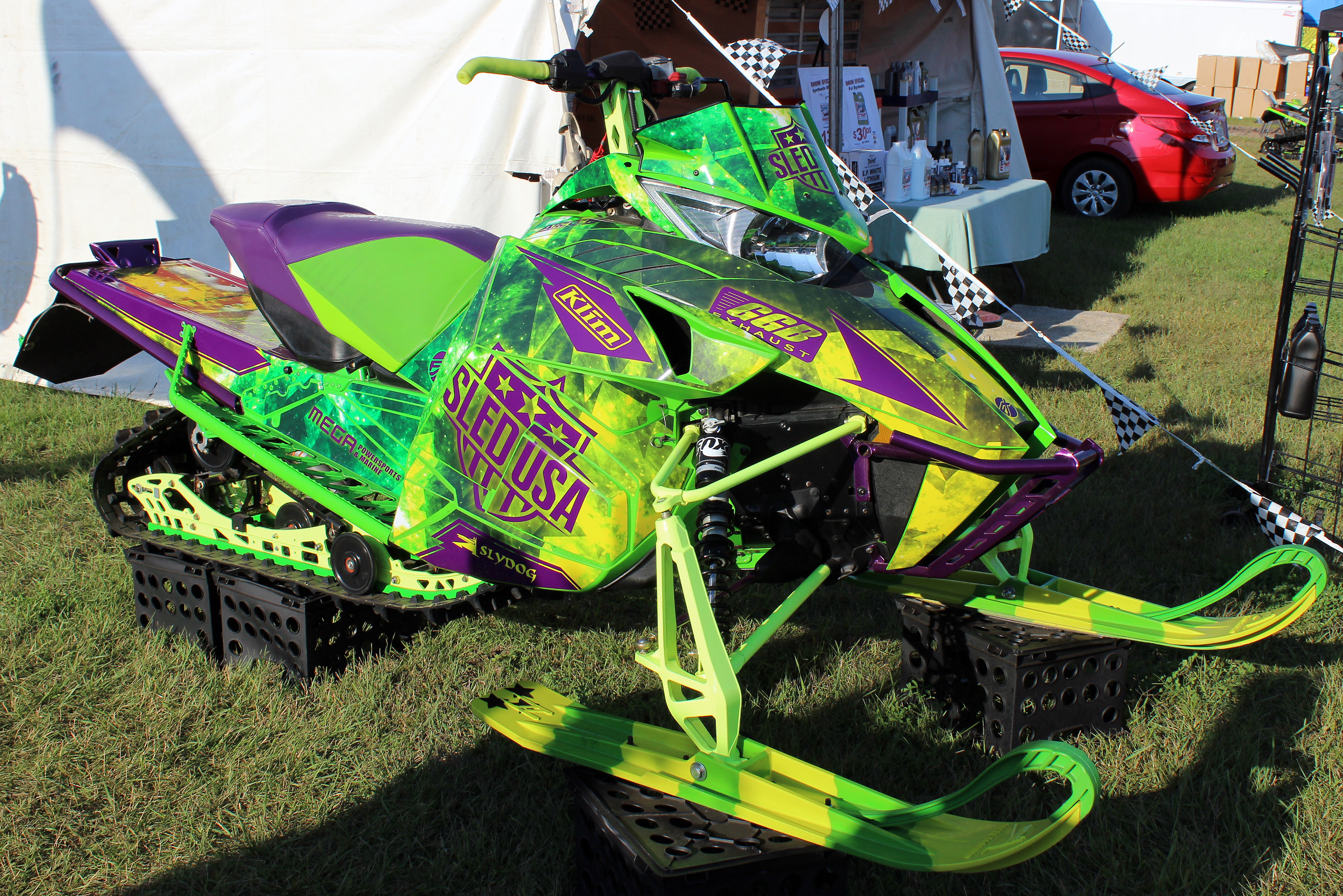 A Arctic Cat Procross snowmobile with a black, purple, and green galaxy Cosmic Camo custom vinyl wrap.