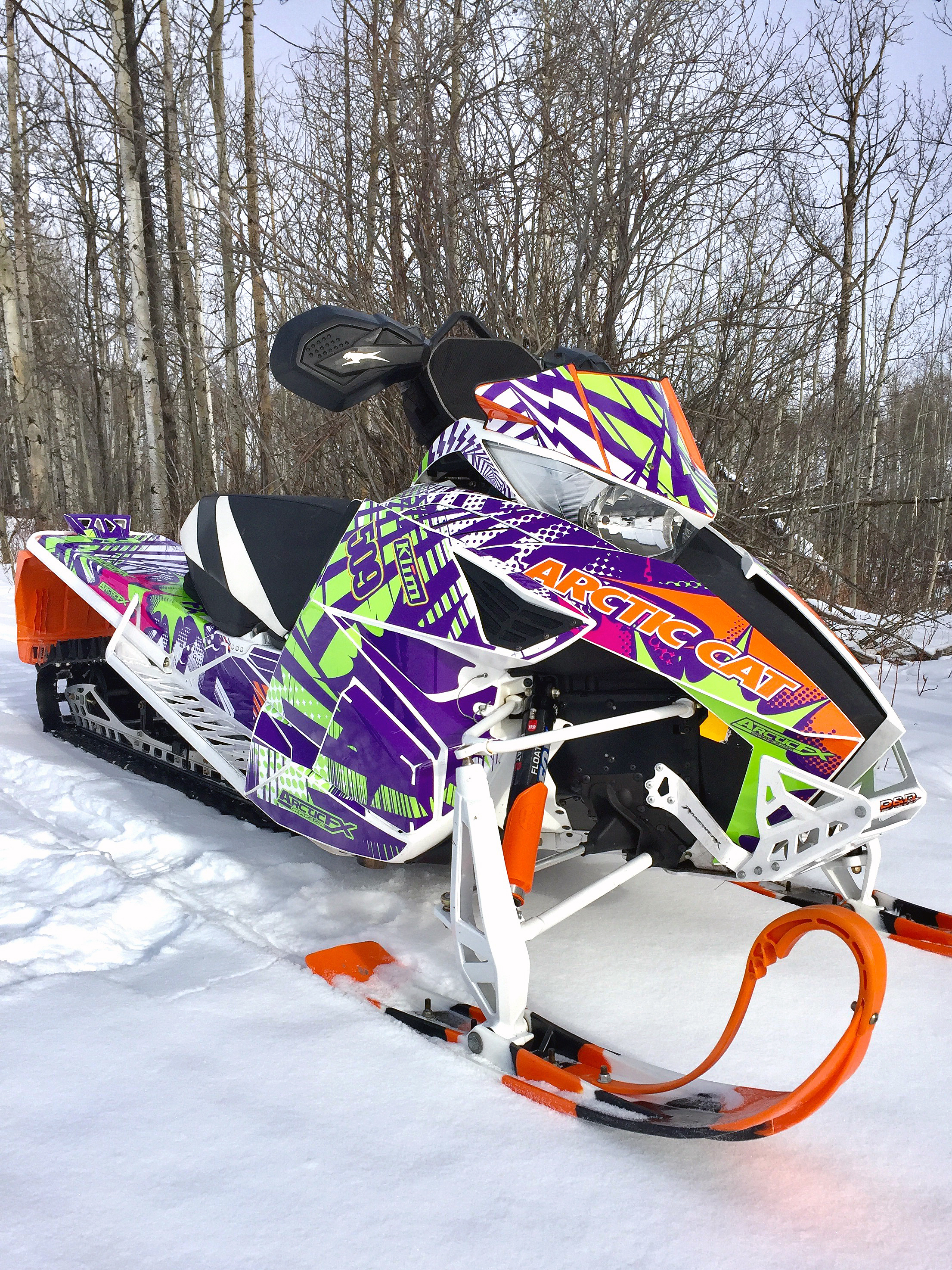 A Arctic Cat Proclimb snowmobile with a green, purple and orange grunge halftone Delirious custom vinyl wrap.