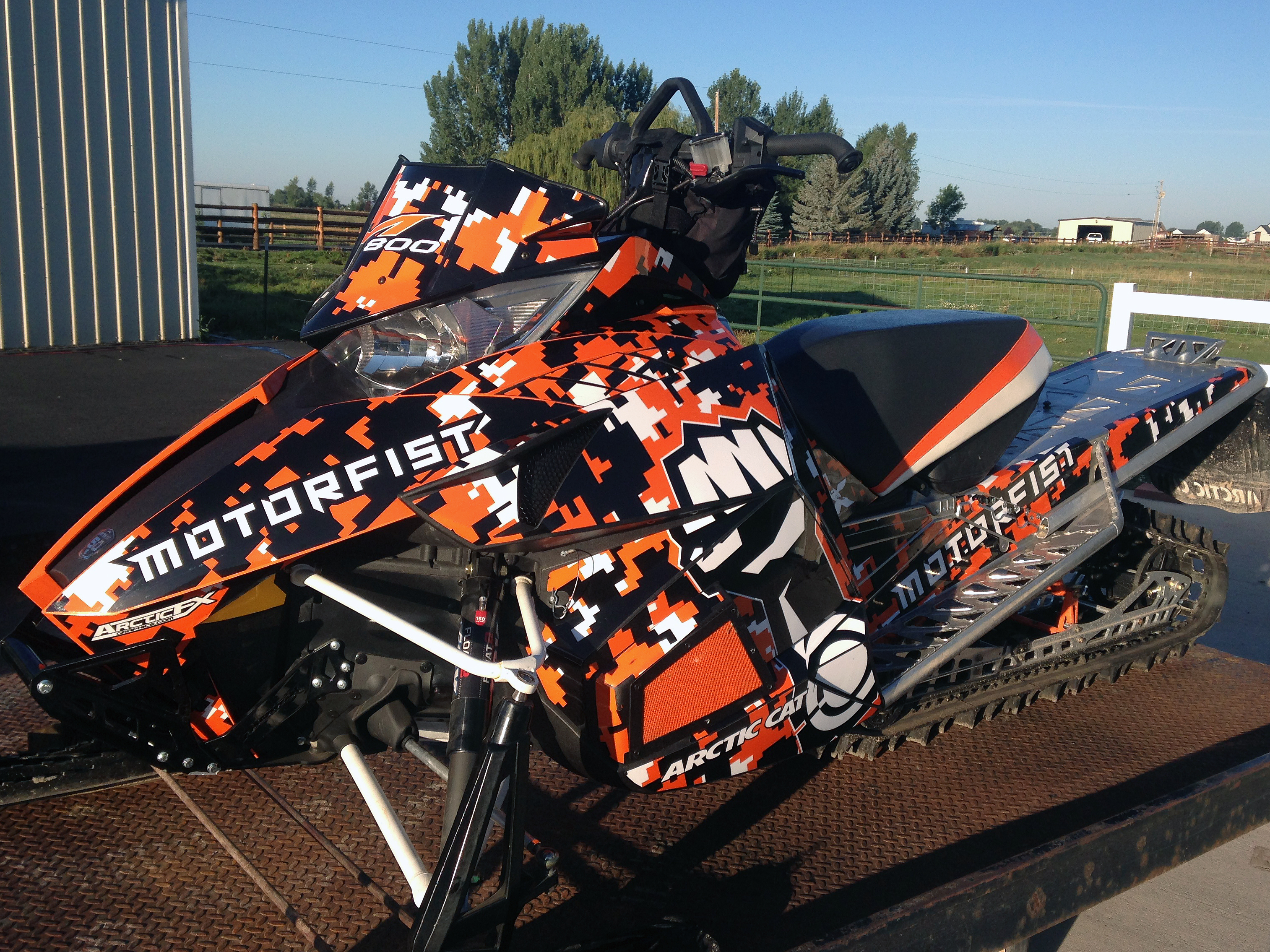 A Arctic Cat Proclimb snowmobile with a orange, white and black pattern digital camo custom vinyl wrap.