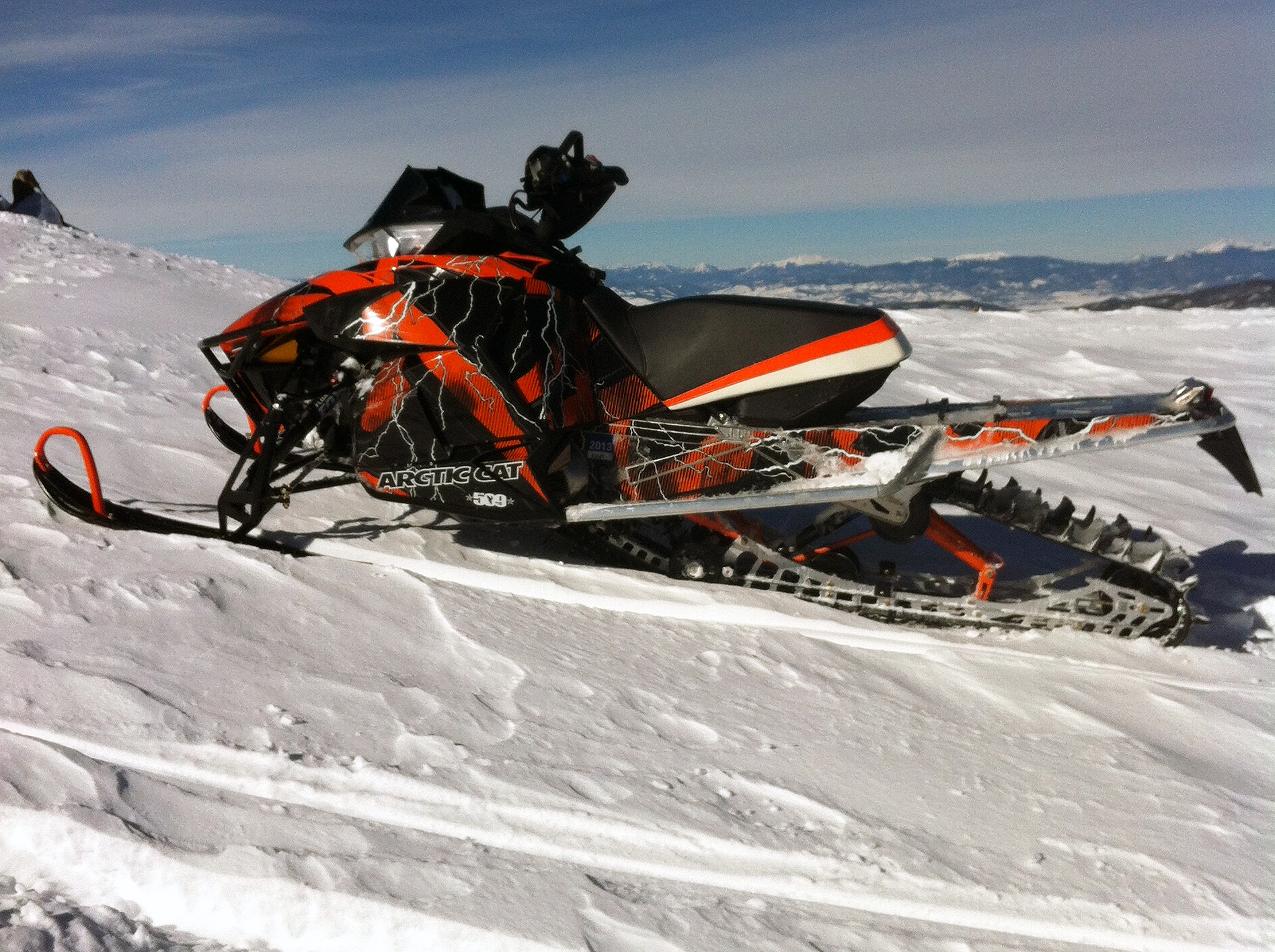 A Arctic Cat Proclimb snowmobile with a orange, white and black lightning Hard Rain custom vinyl wrap.