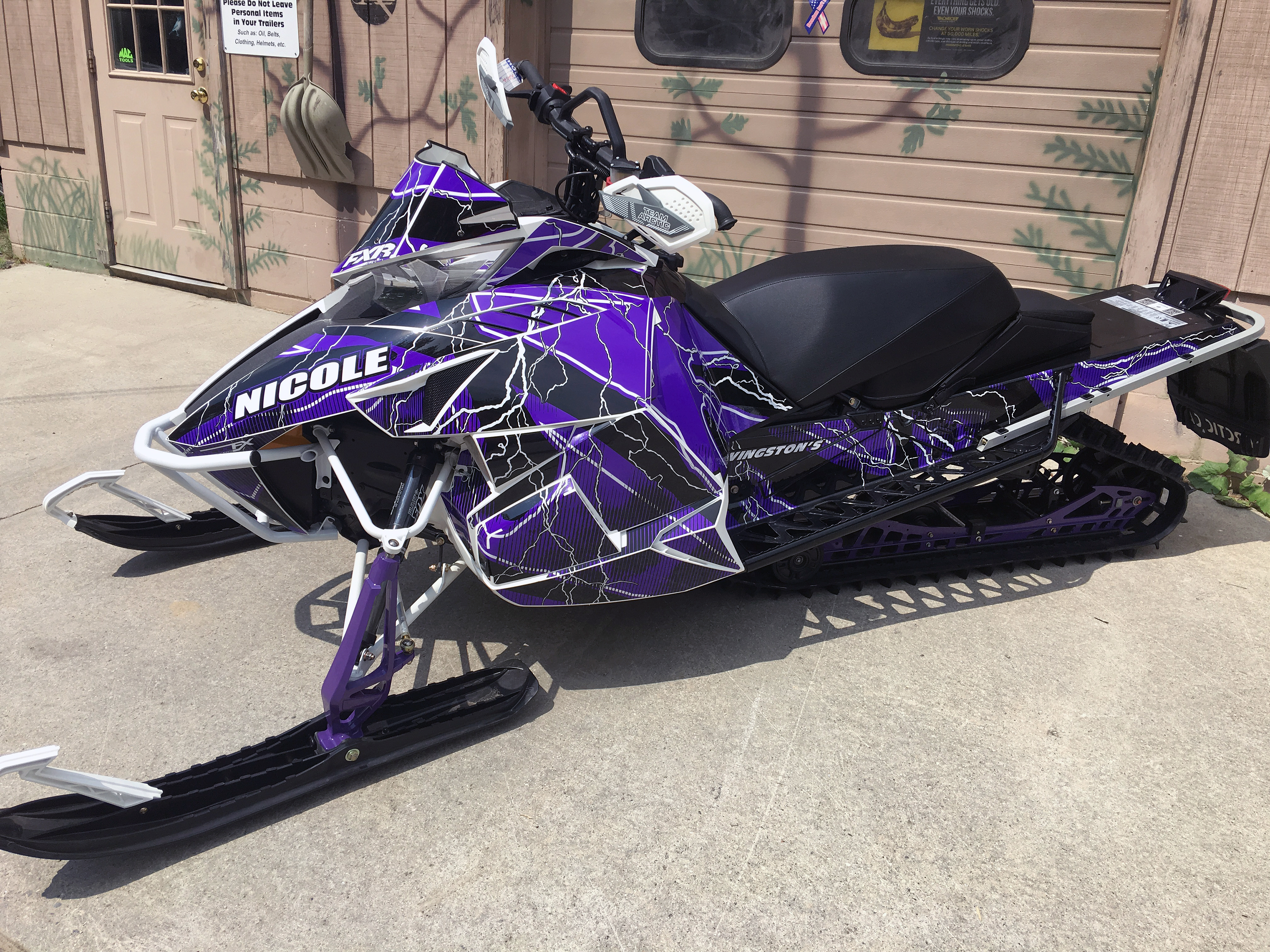 A Arctic Cat Proclimb snowmobile with a purple, white and black lightning Hard Rain custom vinyl wrap.