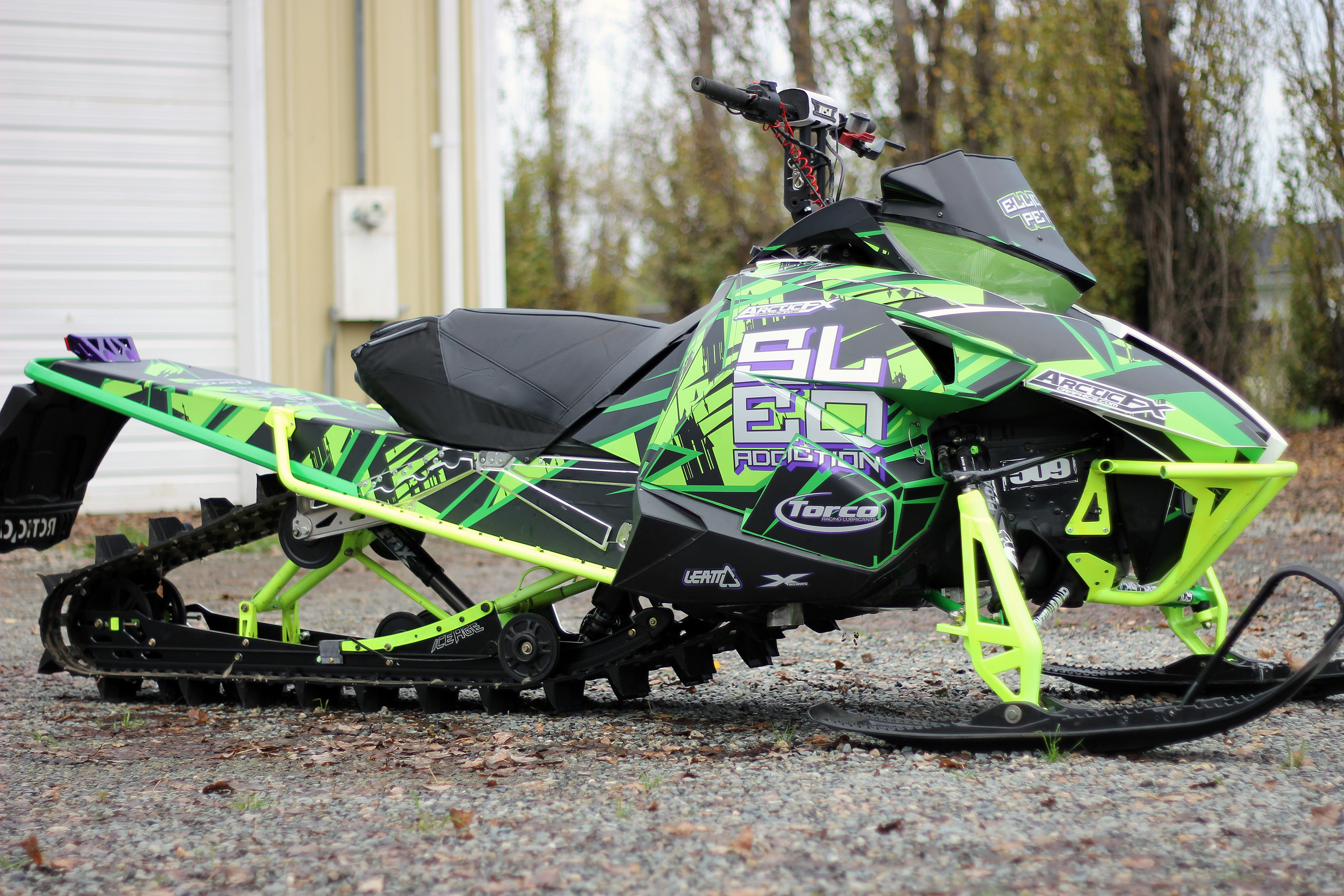 A Arctic Cat Proclimb snowmobile with a green, purple and black arrows Insidious custom vinyl wrap.