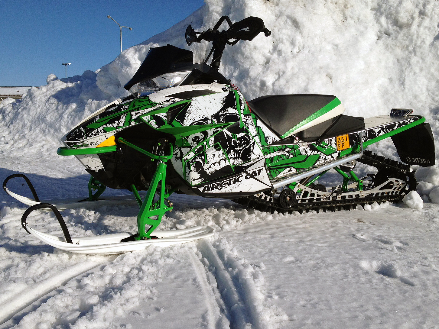 A Arctic Cat Proclimb snowmobile with a green, white and black grunge skull Jawbone custom vinyl wrap.