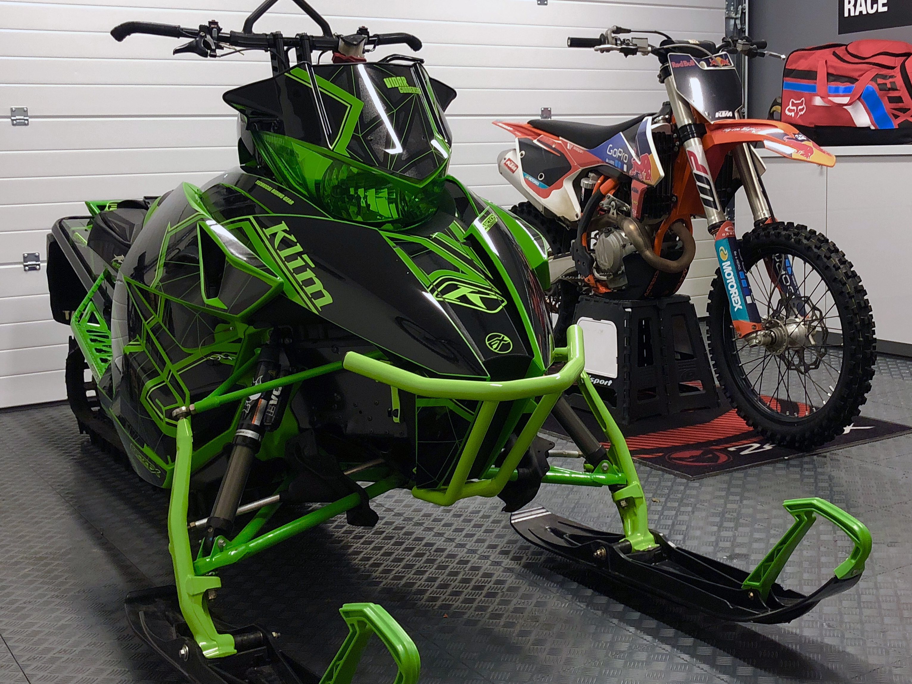 A Arctic Cat Proclimb snowmobile with a green and black geometric line Klim Demolish custom vinyl wrap.