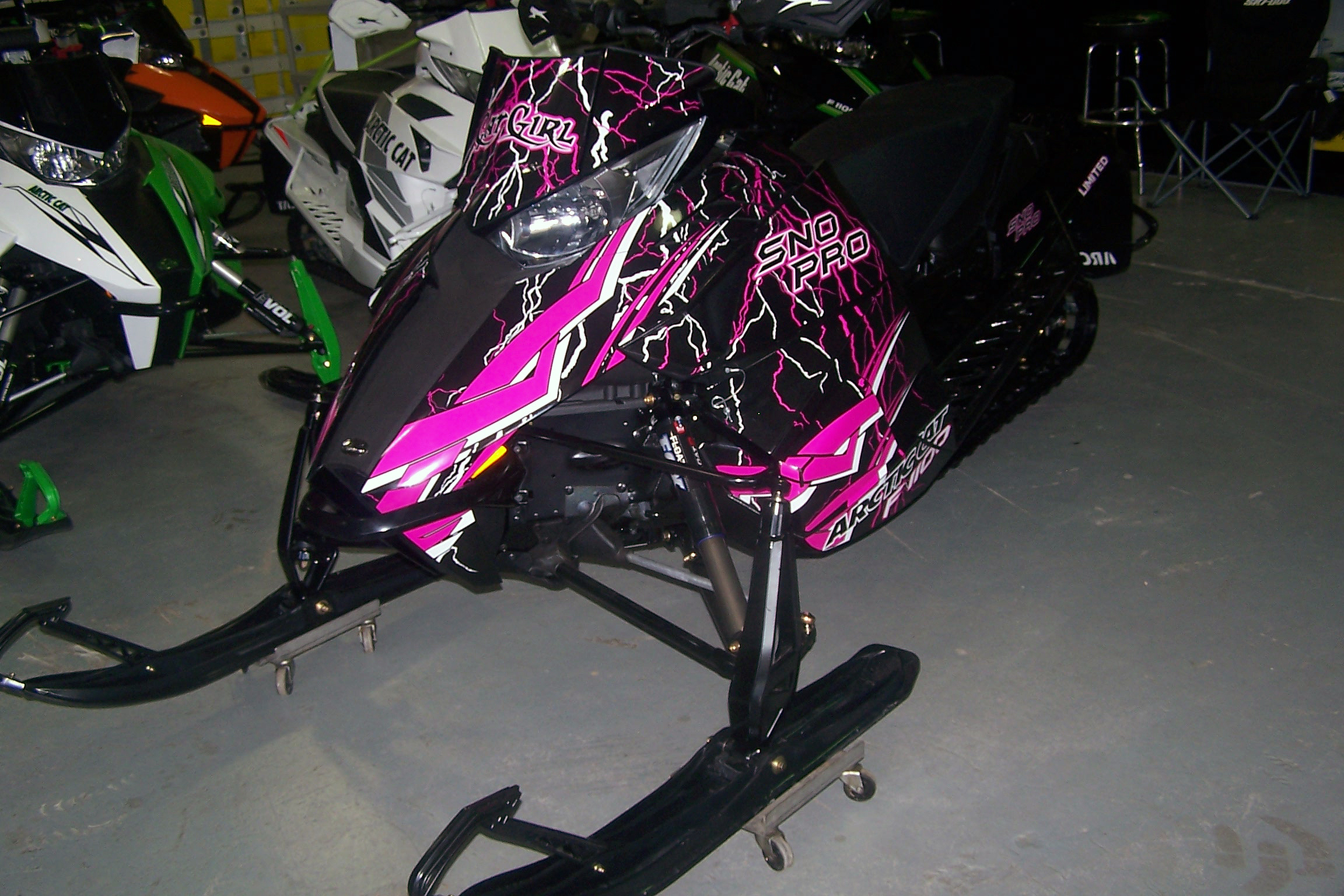 A Arctic Cat Procross snowmobile with a pink, white and black lightning Shock Treatment custom vinyl wrap.