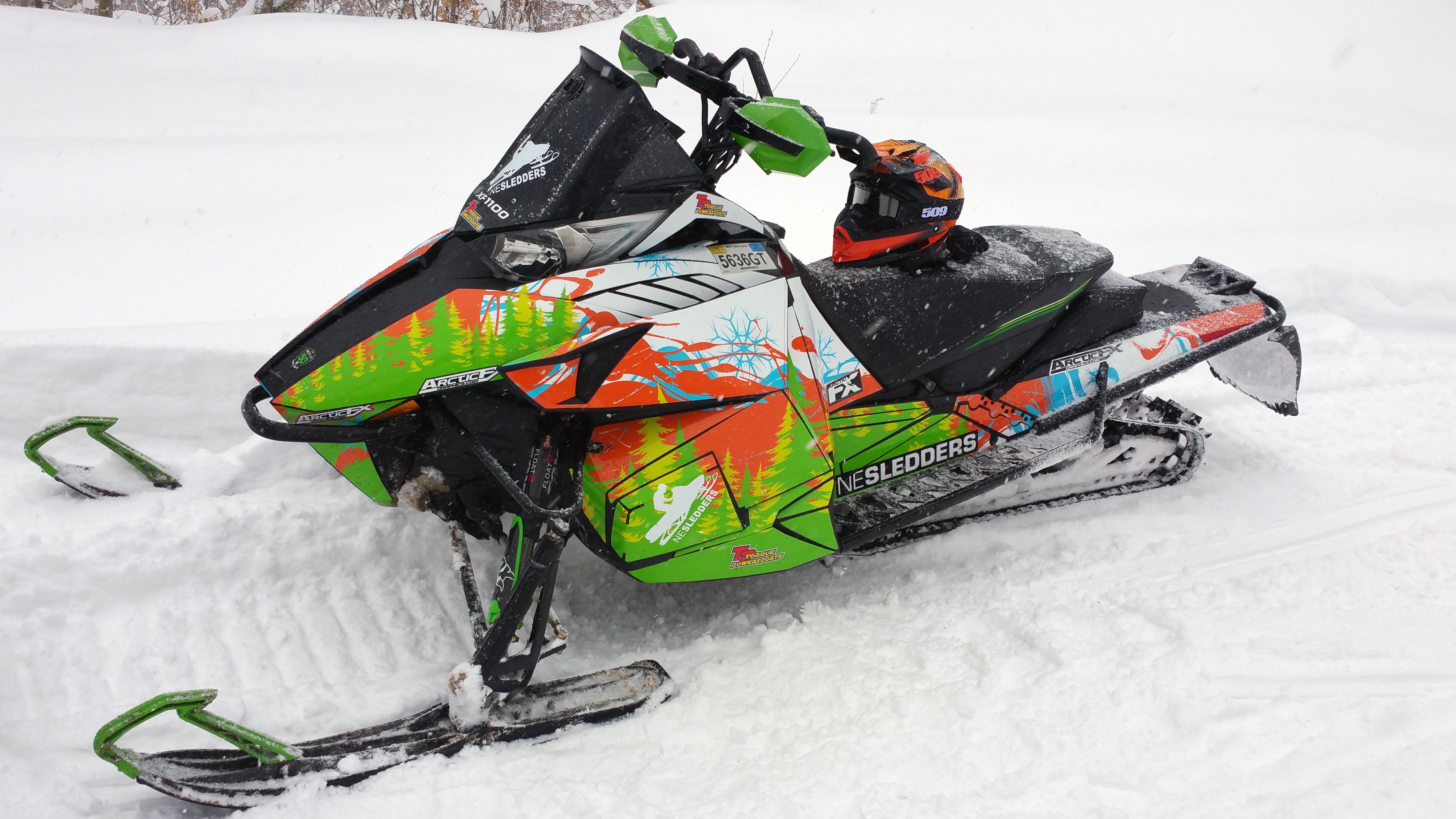 A Arctic Cat Procross snowmobile with a white, orange, and green trees Sub Zero custom vinyl wrap.