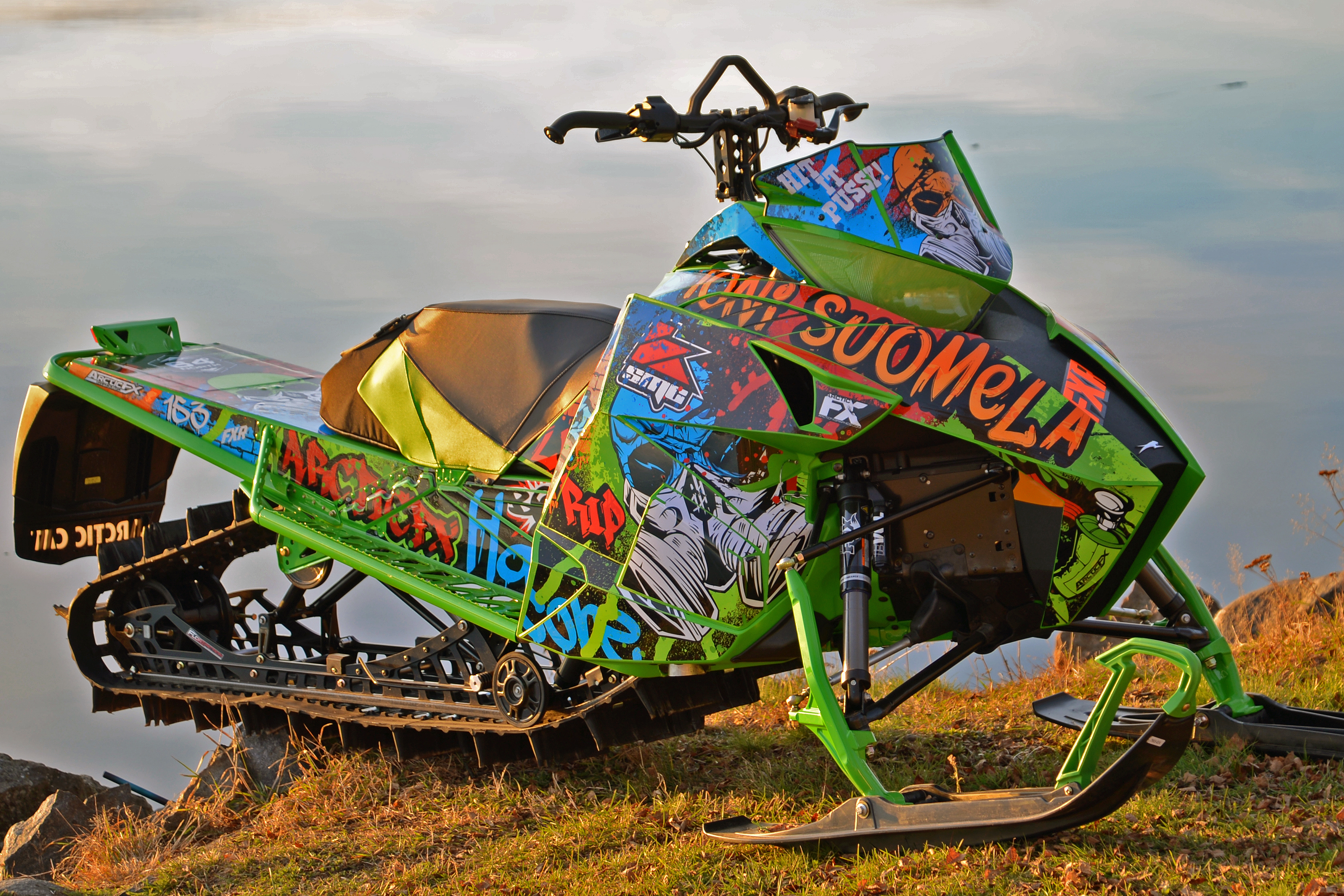 A Arctic Cat Proclimb snowmobile with a green, blue and orange grunge paint Graffiti custom vinyl wrap.