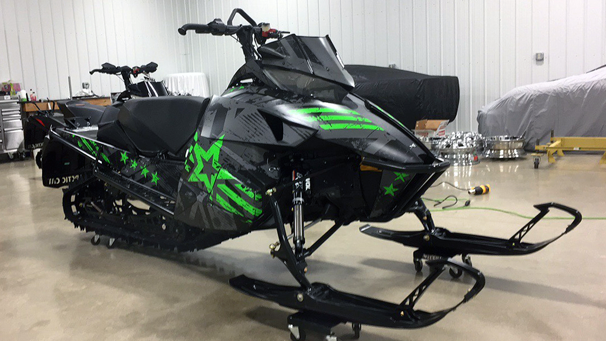 A Arctic Cat Proclimb snowmobile with a gray, green, and black grunge star Wartorn custom vinyl wrap.