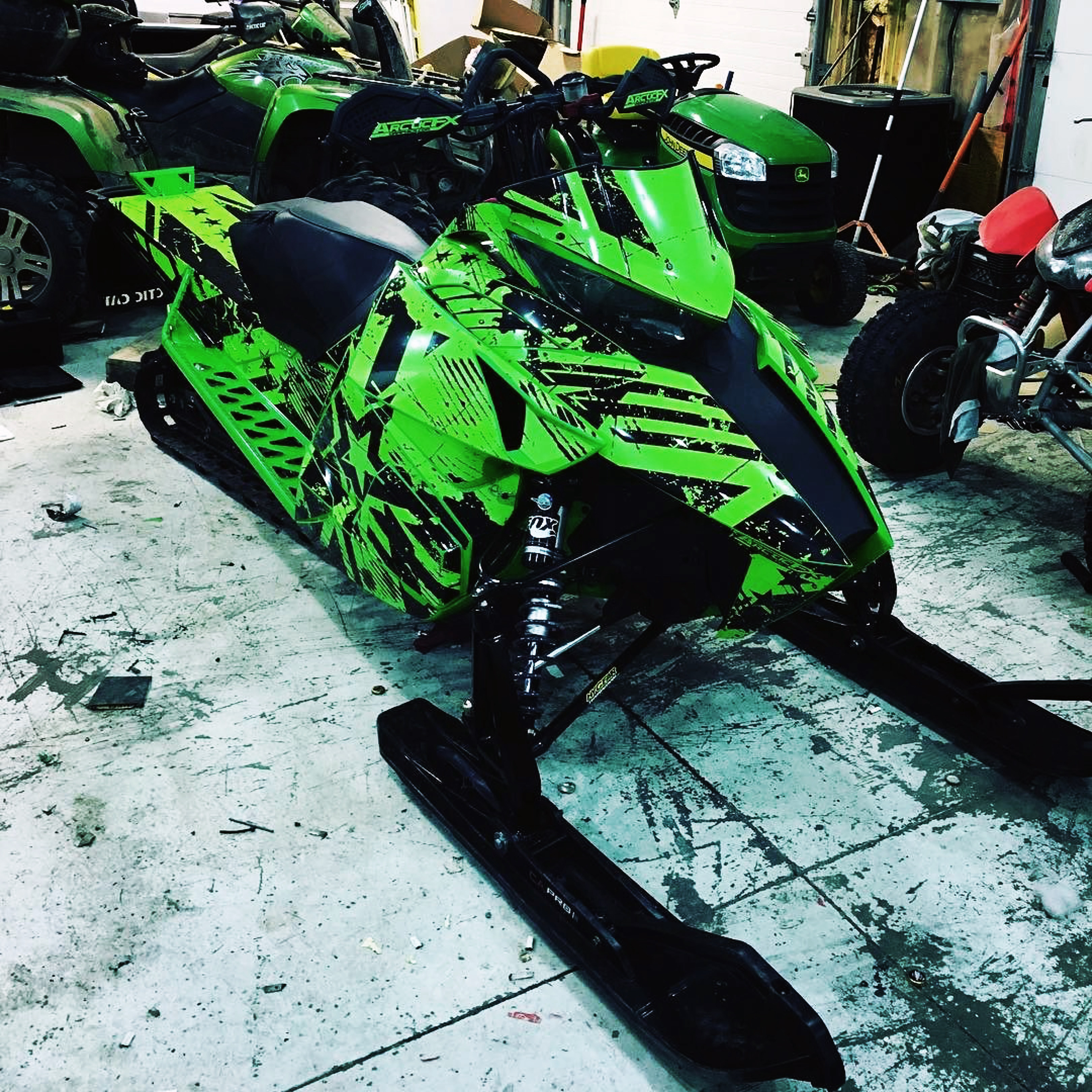 A Arctic Cat Proclimb snowmobile with a green and black grunge star Wartorn custom vinyl wrap.