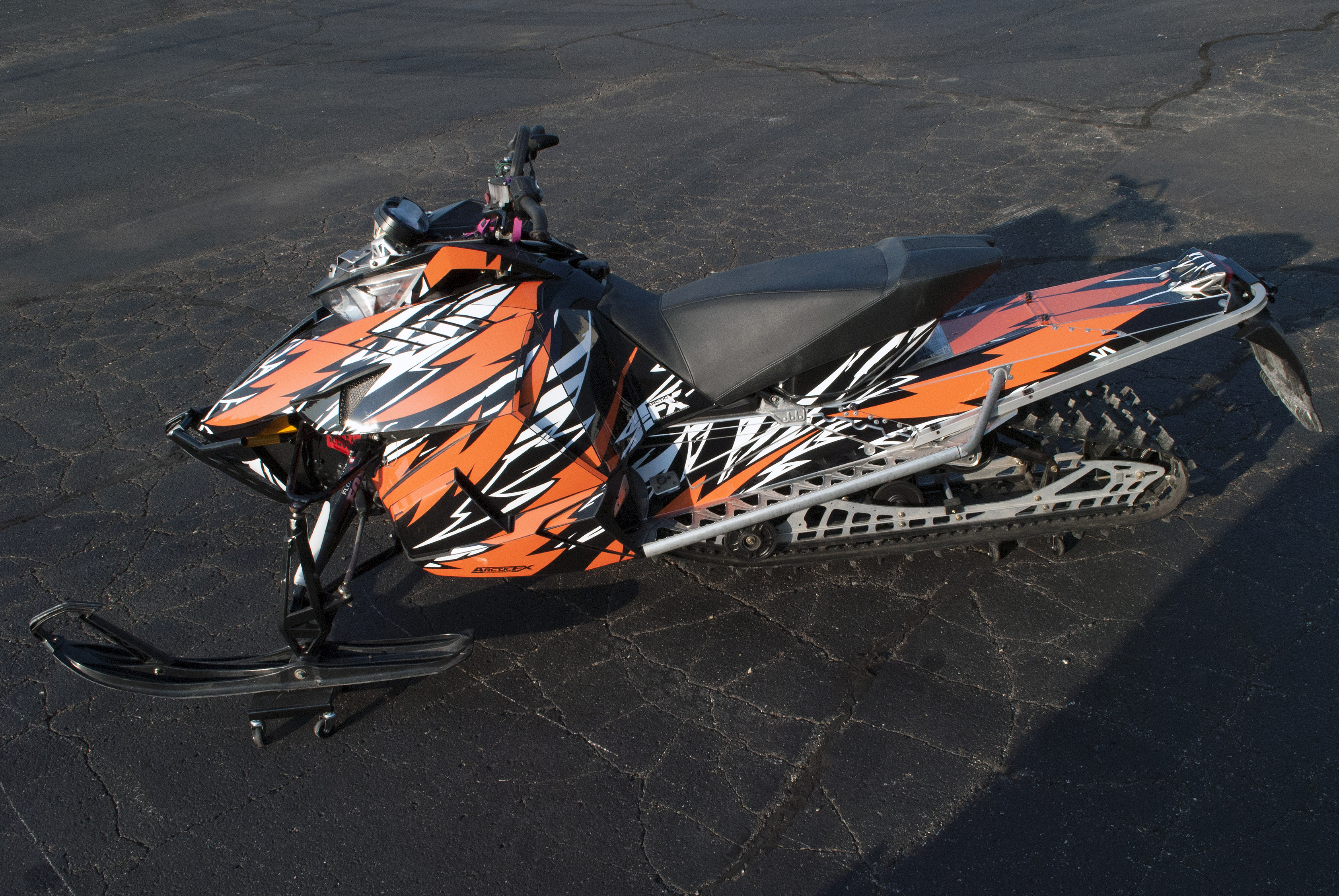 A Arctic Cat Procross snowmobile with a orange, white and black lightning Bolts and Wings custom vinyl wrap.